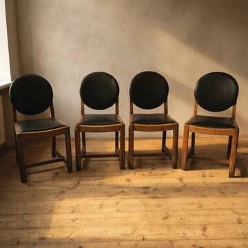 Set of four vintage wooden dining chairs with black leather upholstery
