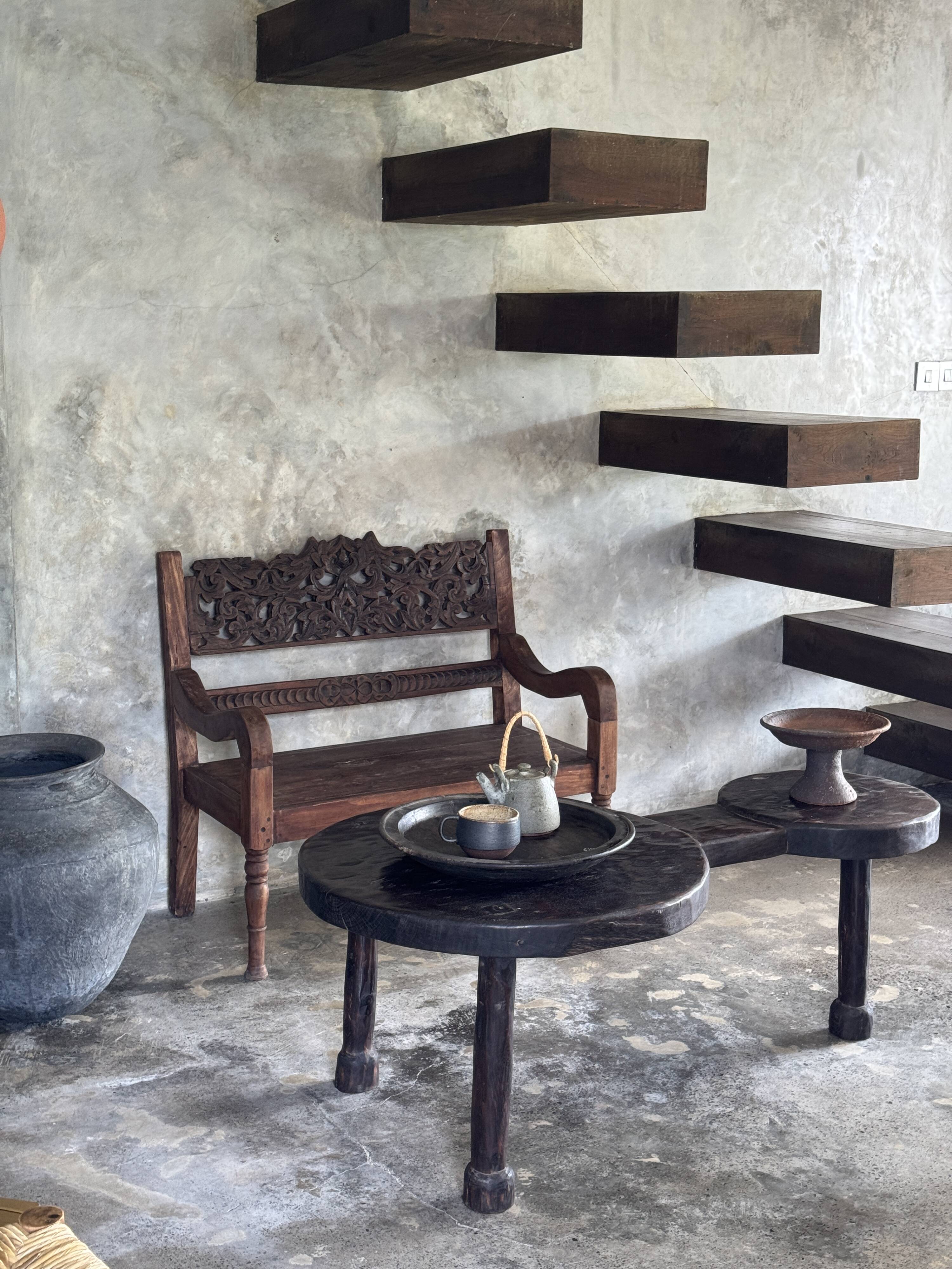 Small antique Indonesian bench in carved teak with plant and floral motifs.