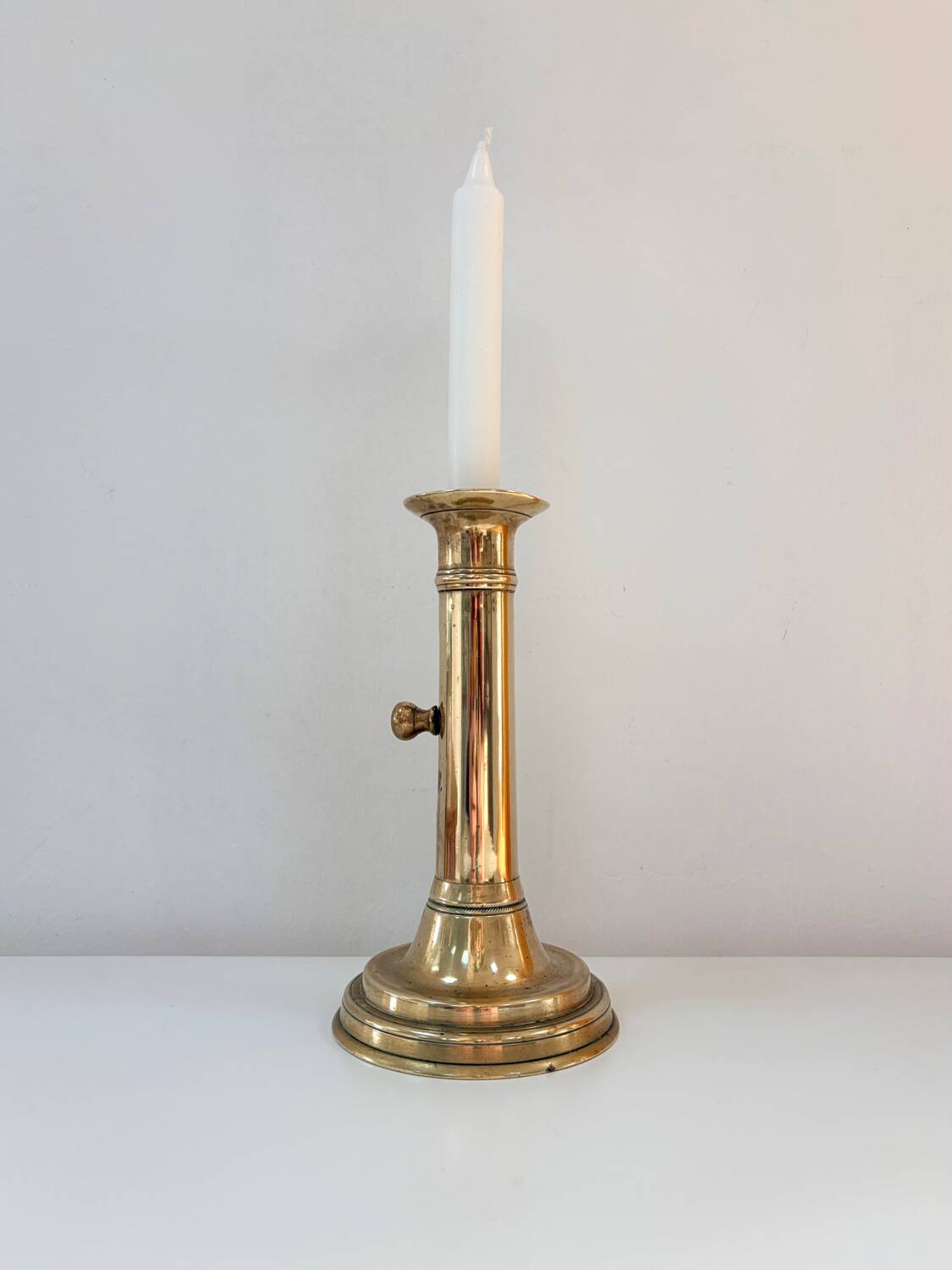 Old brass candlestick with push button.