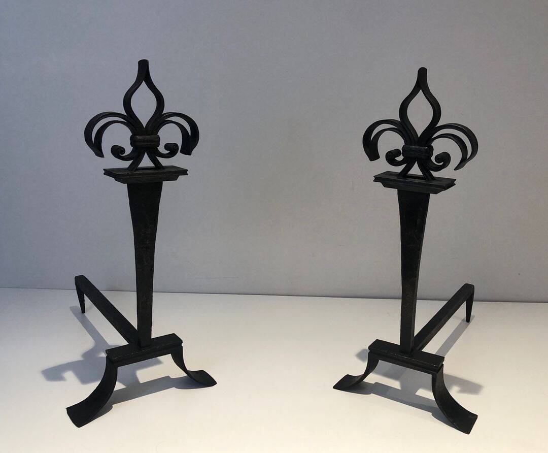 Important pair of wrought iron andirons with torch in heraldic fleur-de-lis design.