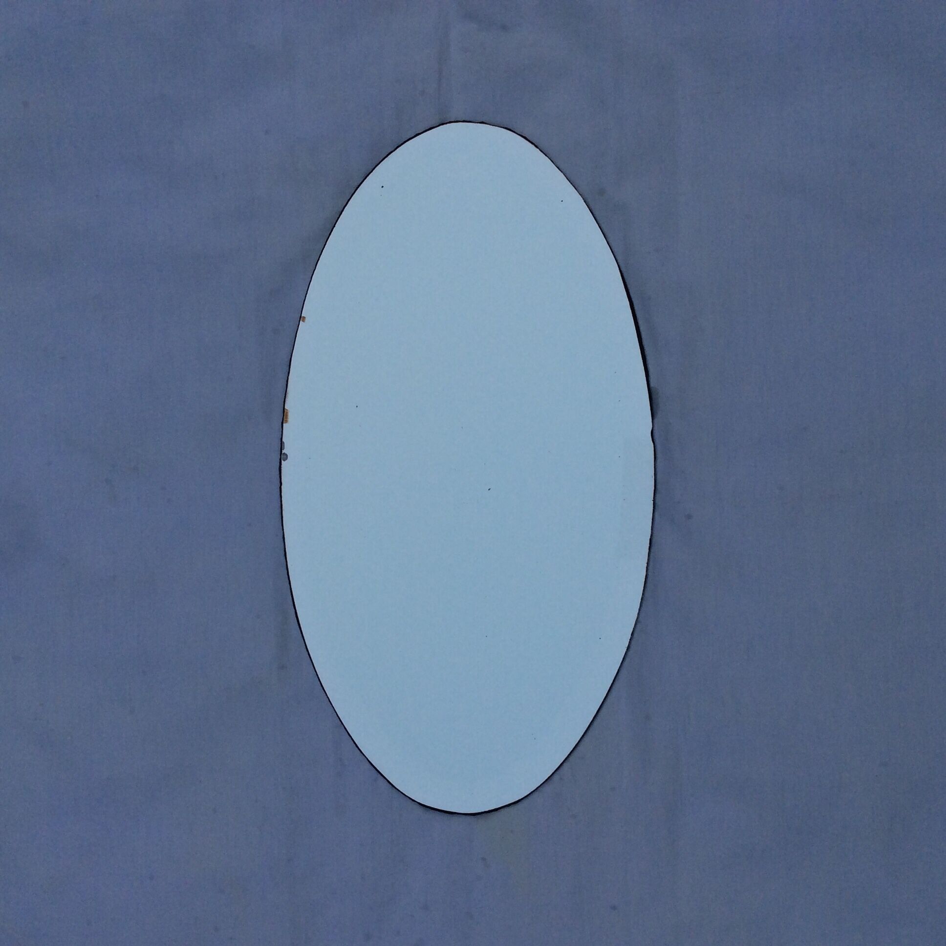 Beveled oval mirror stitched at the edges around the 1930