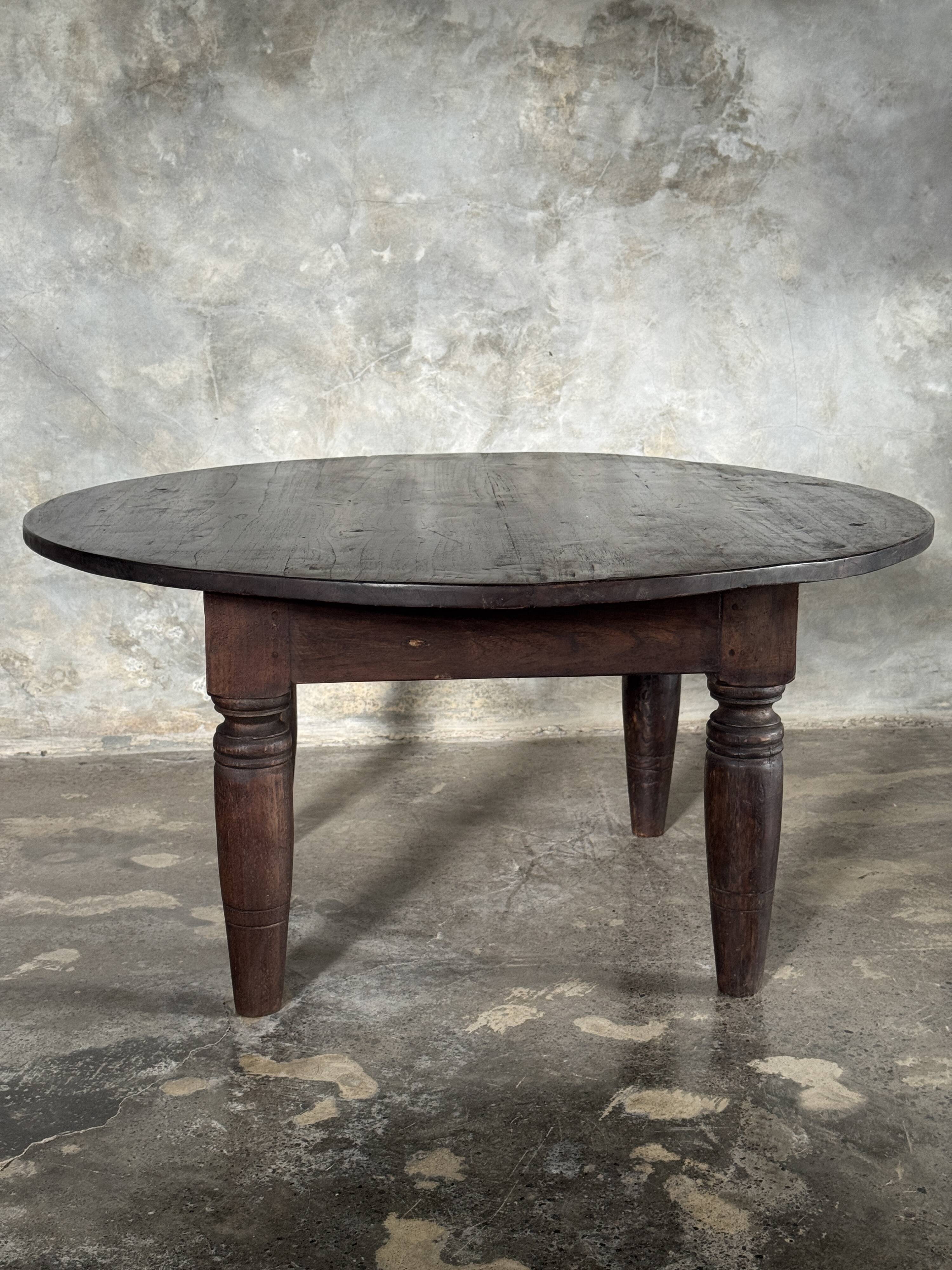 Antique round coffee table in Indonesian teak with turned legs.