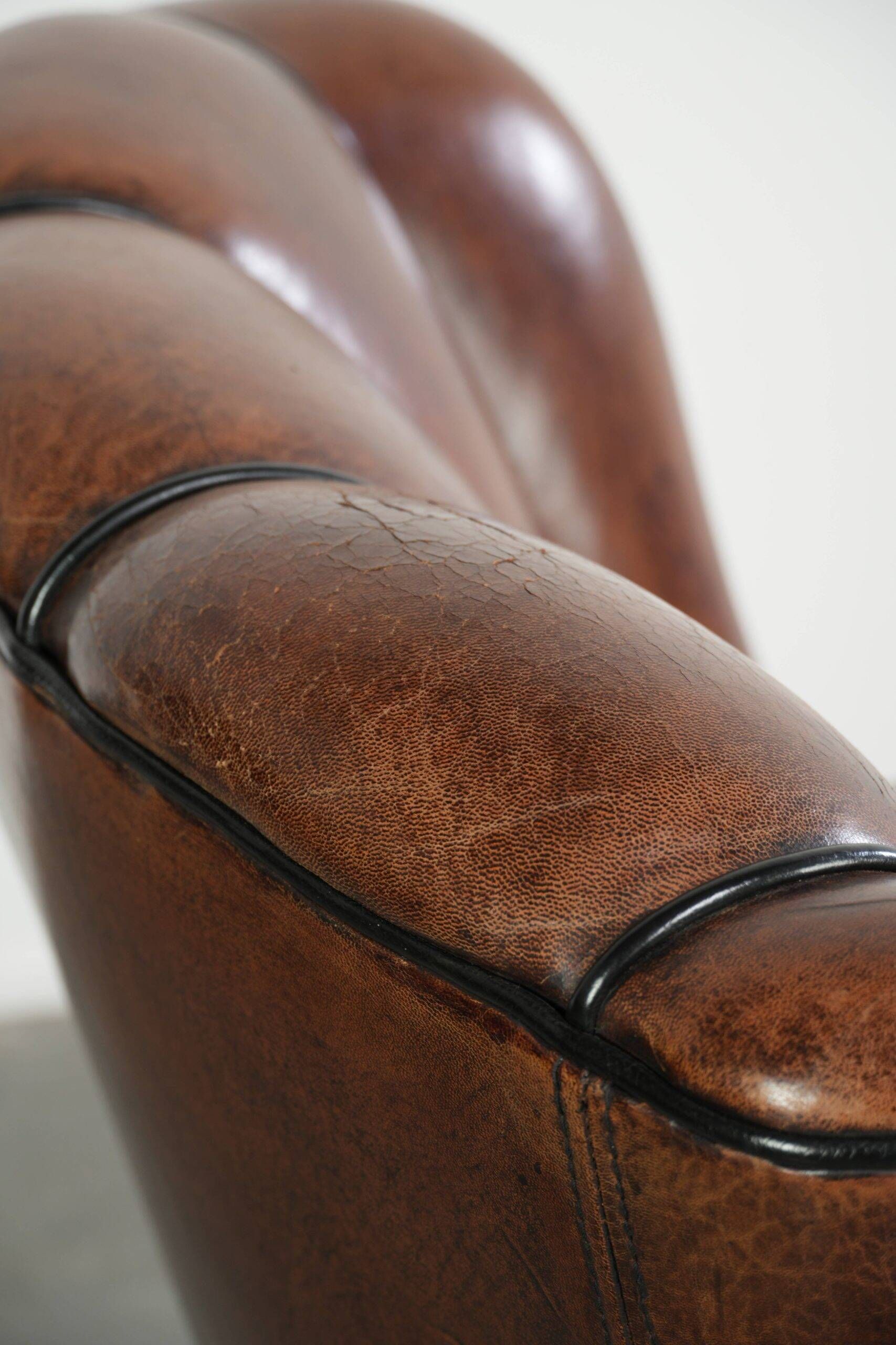 Fauteuil en peau de mouton confortable au design unique, fini avec un passepoil noir.