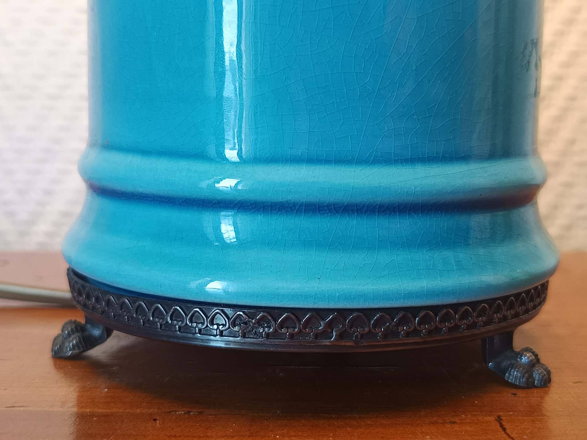 Blue ceramic lamp with claw feet and foliage lampshade.