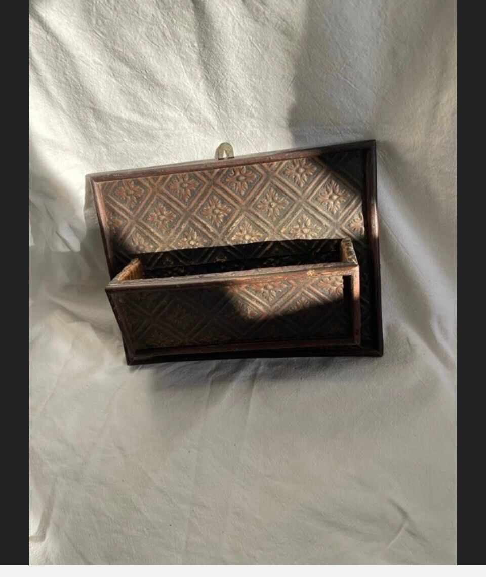 Hammered leather wall mail holder on wood.