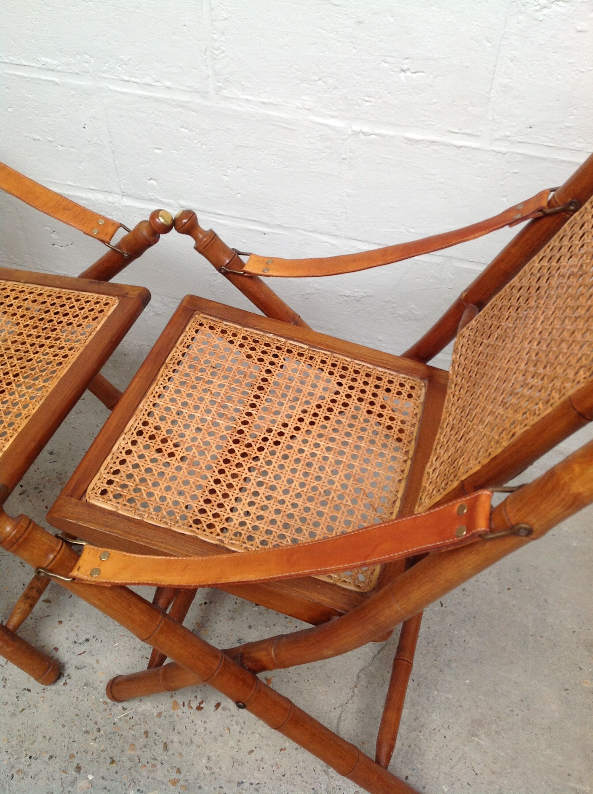 Pair of folding chairs in bamboo and caning, leather and brass