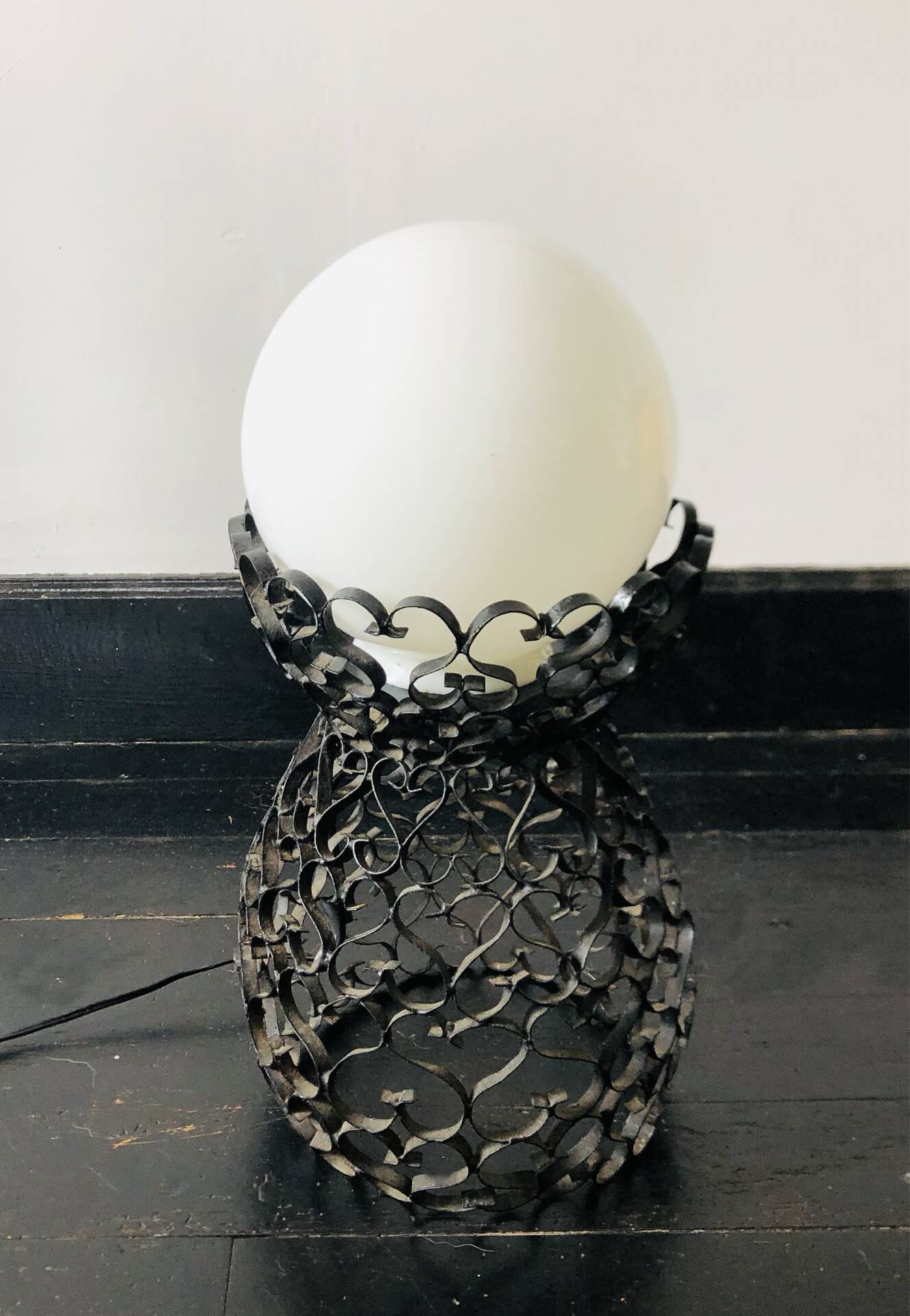 Handcrafted wrought iron lamp with a white opaline globe.
