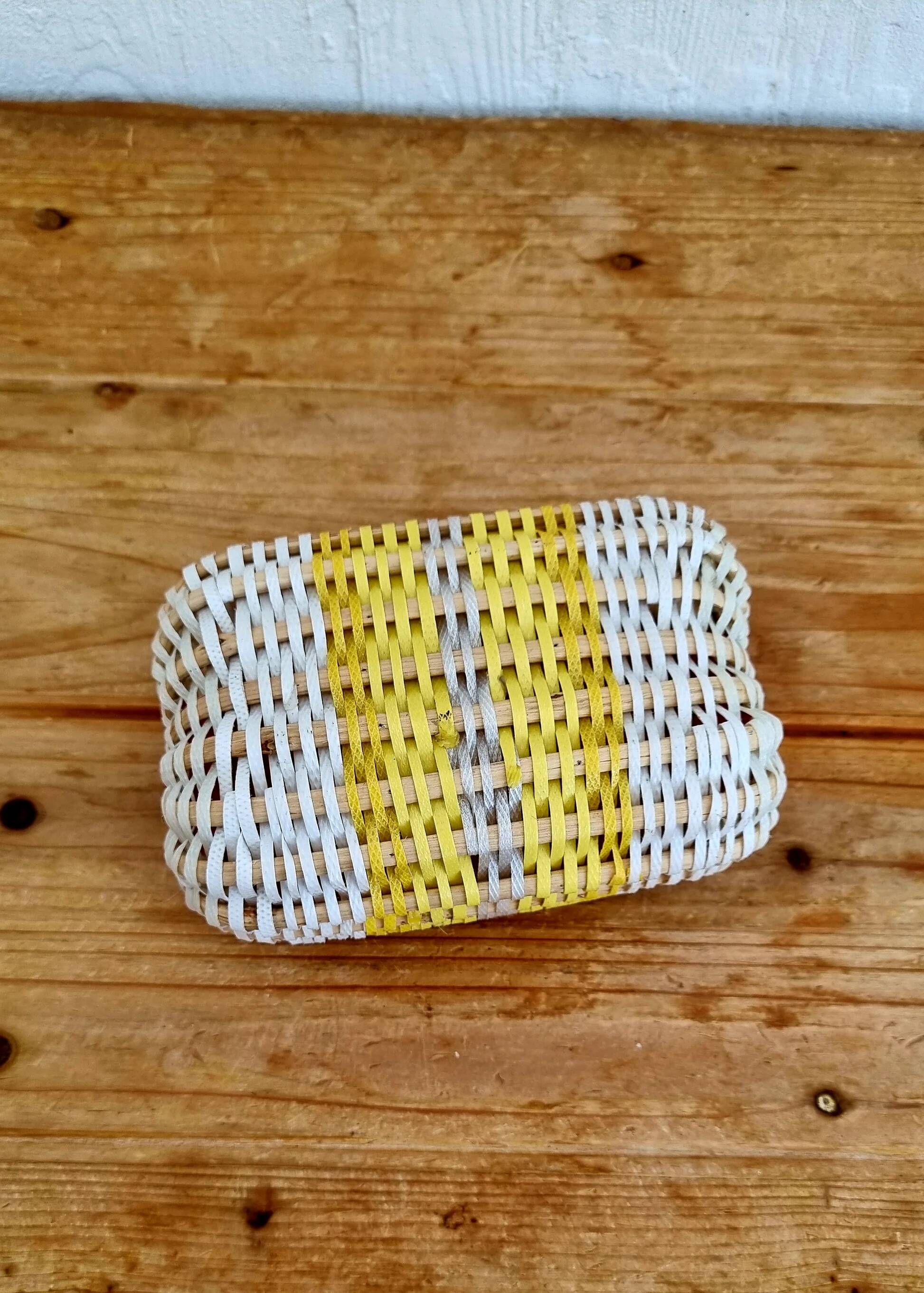 Vintage woven basket in yellow, white, and pink plastic.