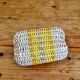 Vintage woven basket in yellow, white, and pink plastic.