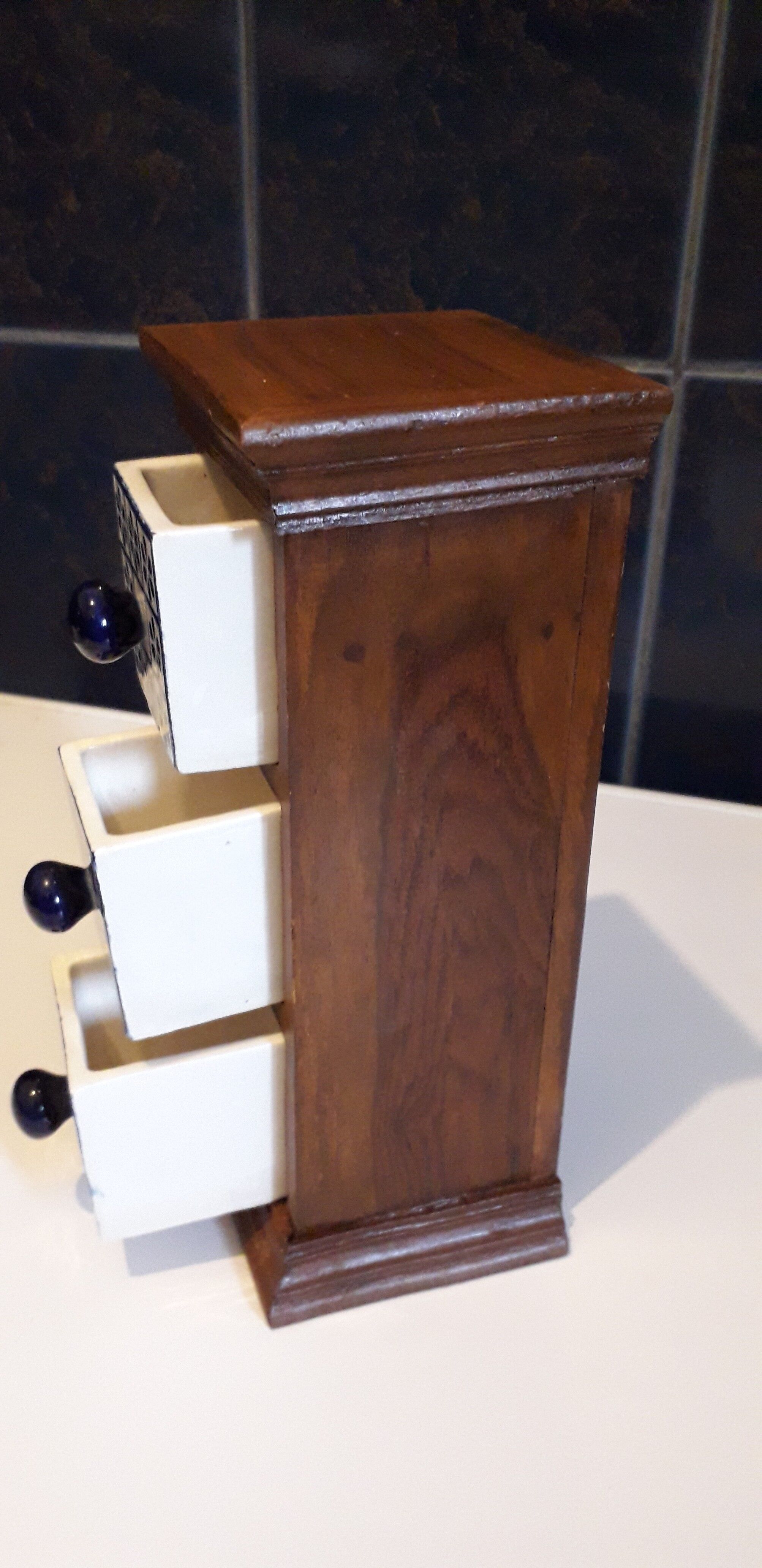 Storage in the form of a small wooden cabinet, with 3 ceramic drawers.