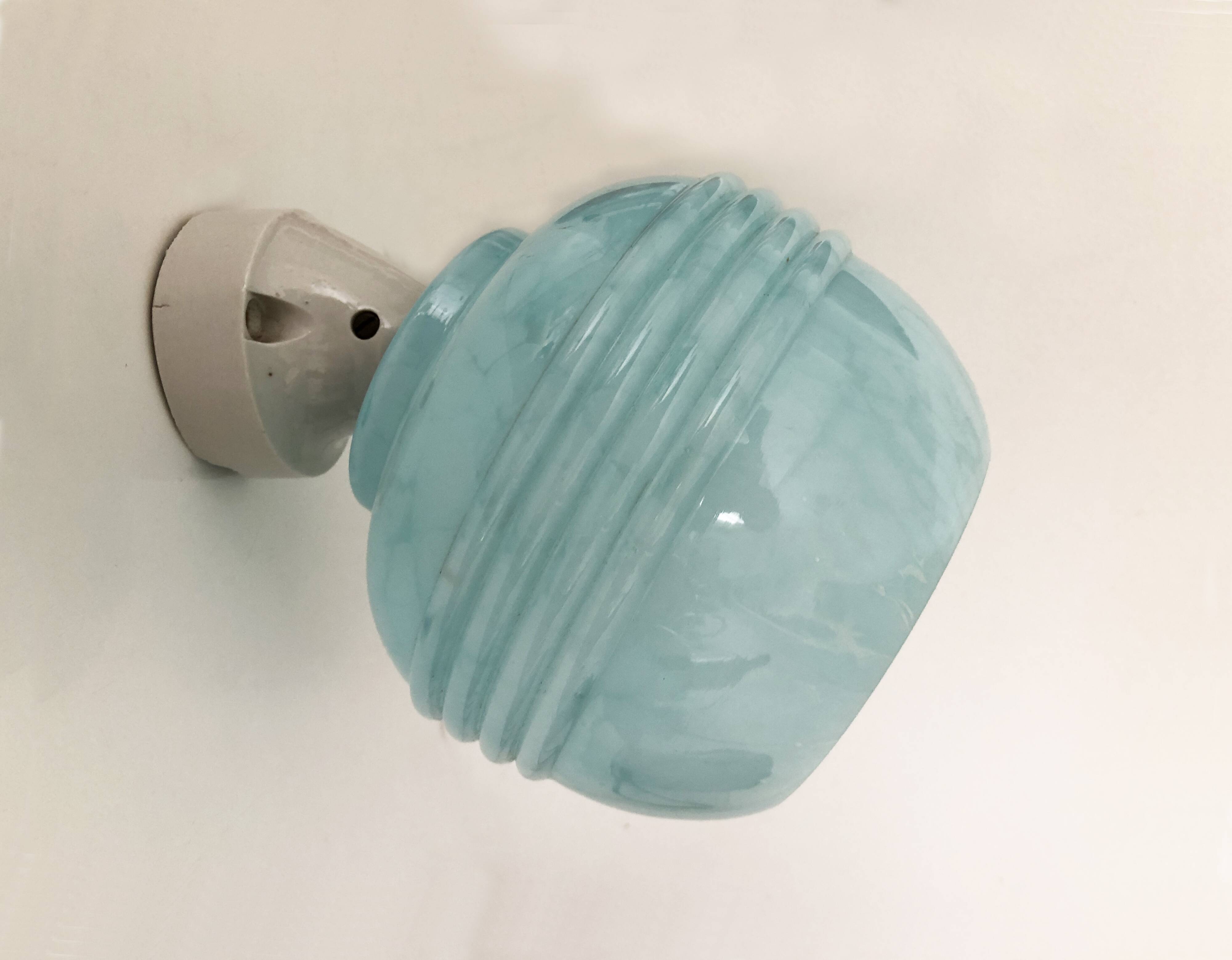 Wall light in ceramic with a light blue glass globe.