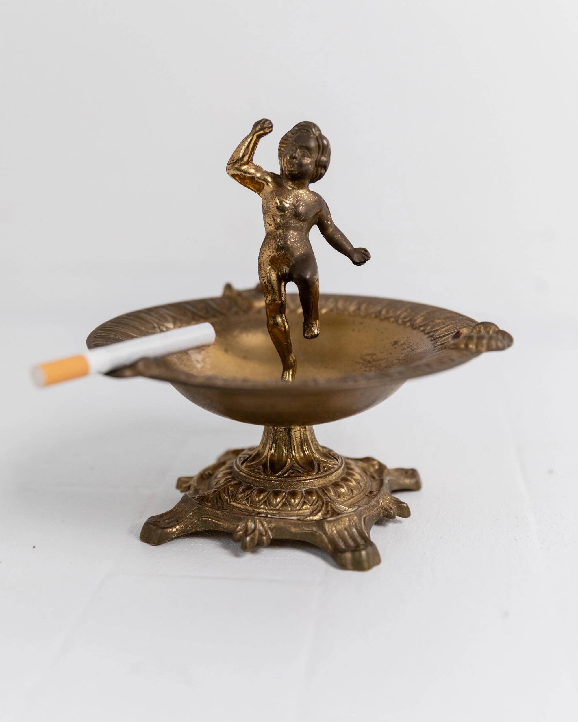 Vintage brass ashtray from the 1940s with a nude boy figurine on a footed base.