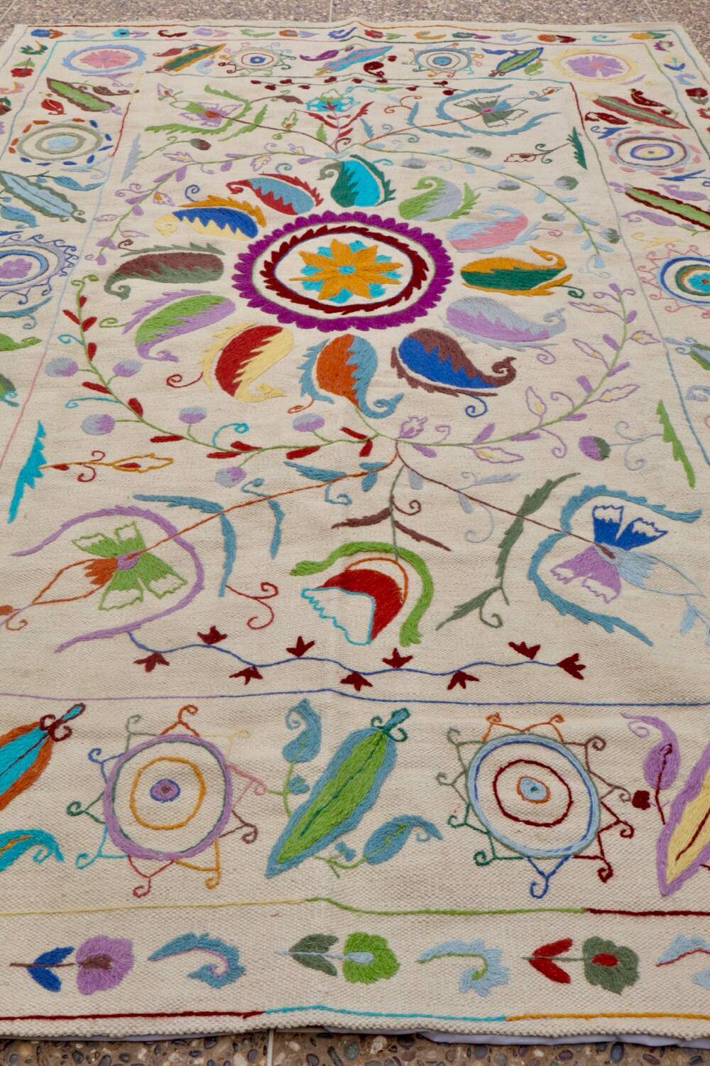 White suzani kilim rug with embroidered multi-colored patterns