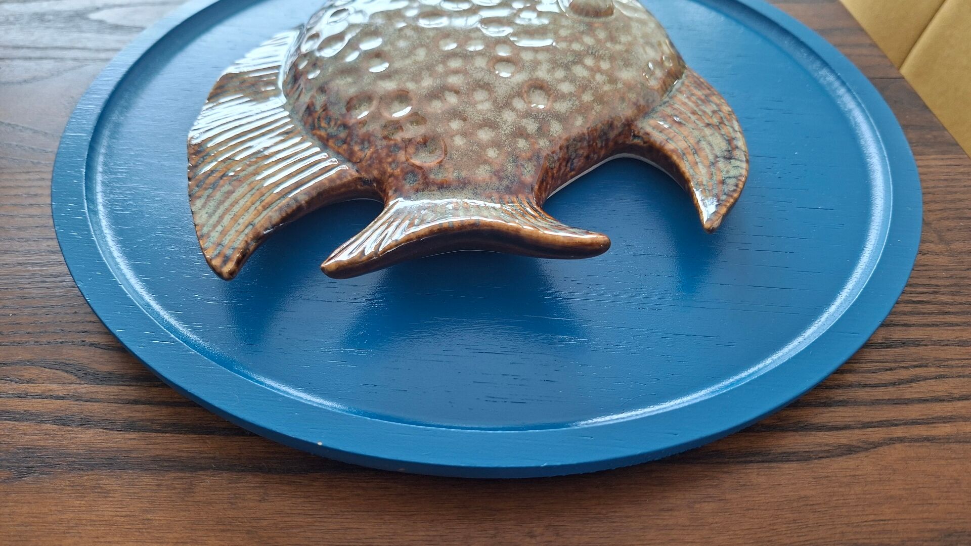 Vallauris ceramic wall sculpture of a relief fish on a blue plaque.