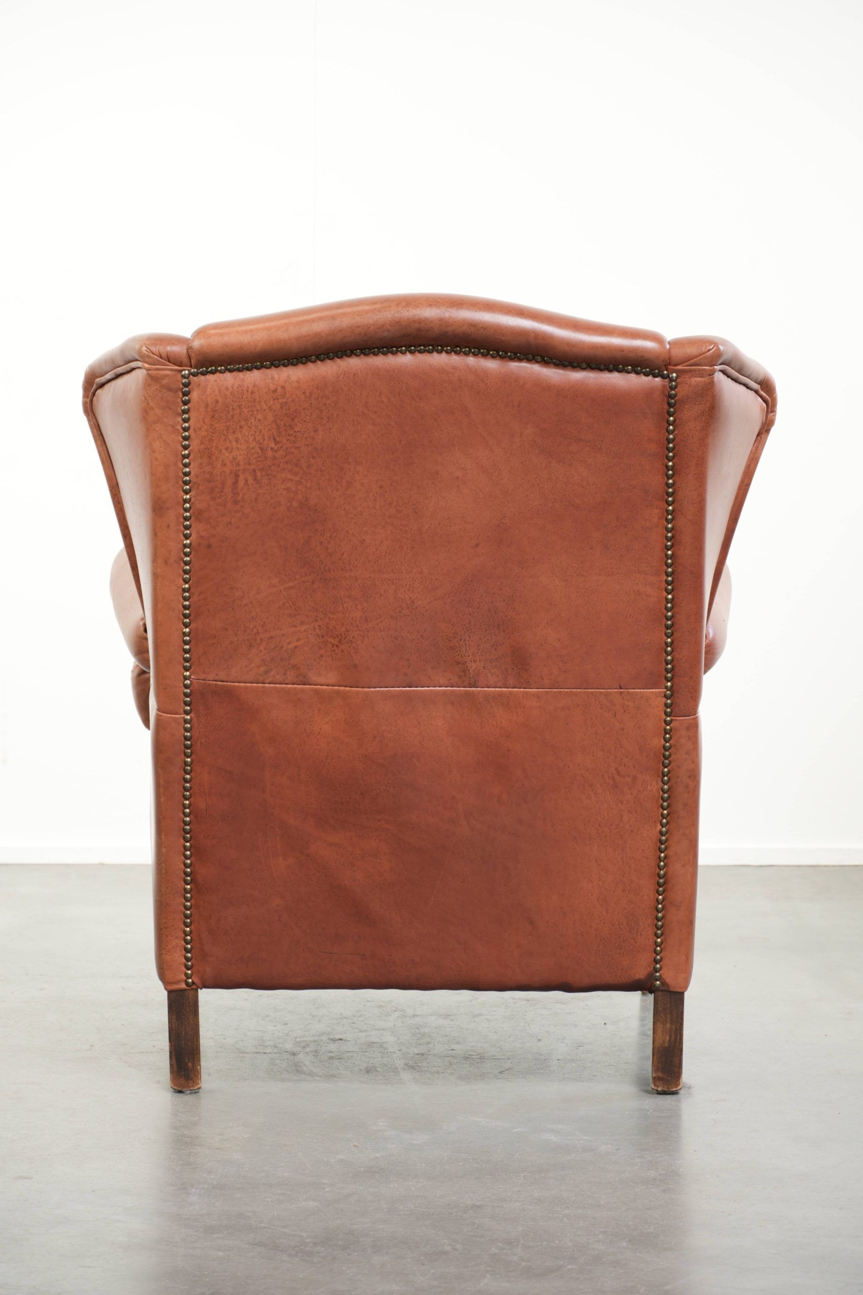 Fauteuil anglais à oreilles de couleur cognac clair en cuir de vache.