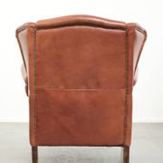 Light cognac-coloured English wingback armchair made of cowhide leather