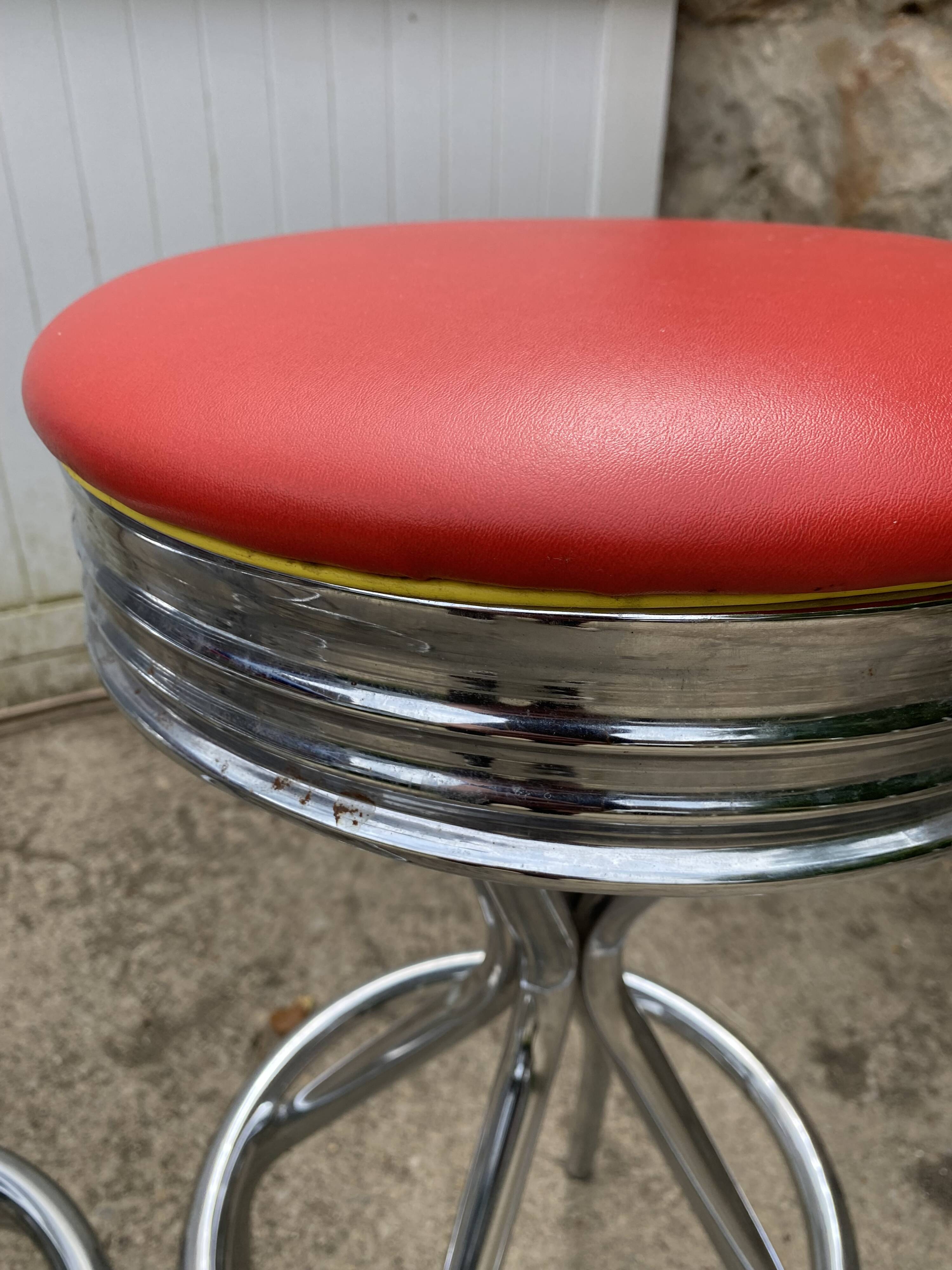Set of 5 vintage swivel bar stools in blue, red, orange, and yellow.