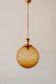 Brass pendant light with a round orange glass shade and a swirling structure.