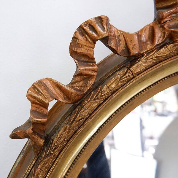 Wear consistent with age and use  Wood and gilded plaster ''Noeud d'Amour'' Oval mirror