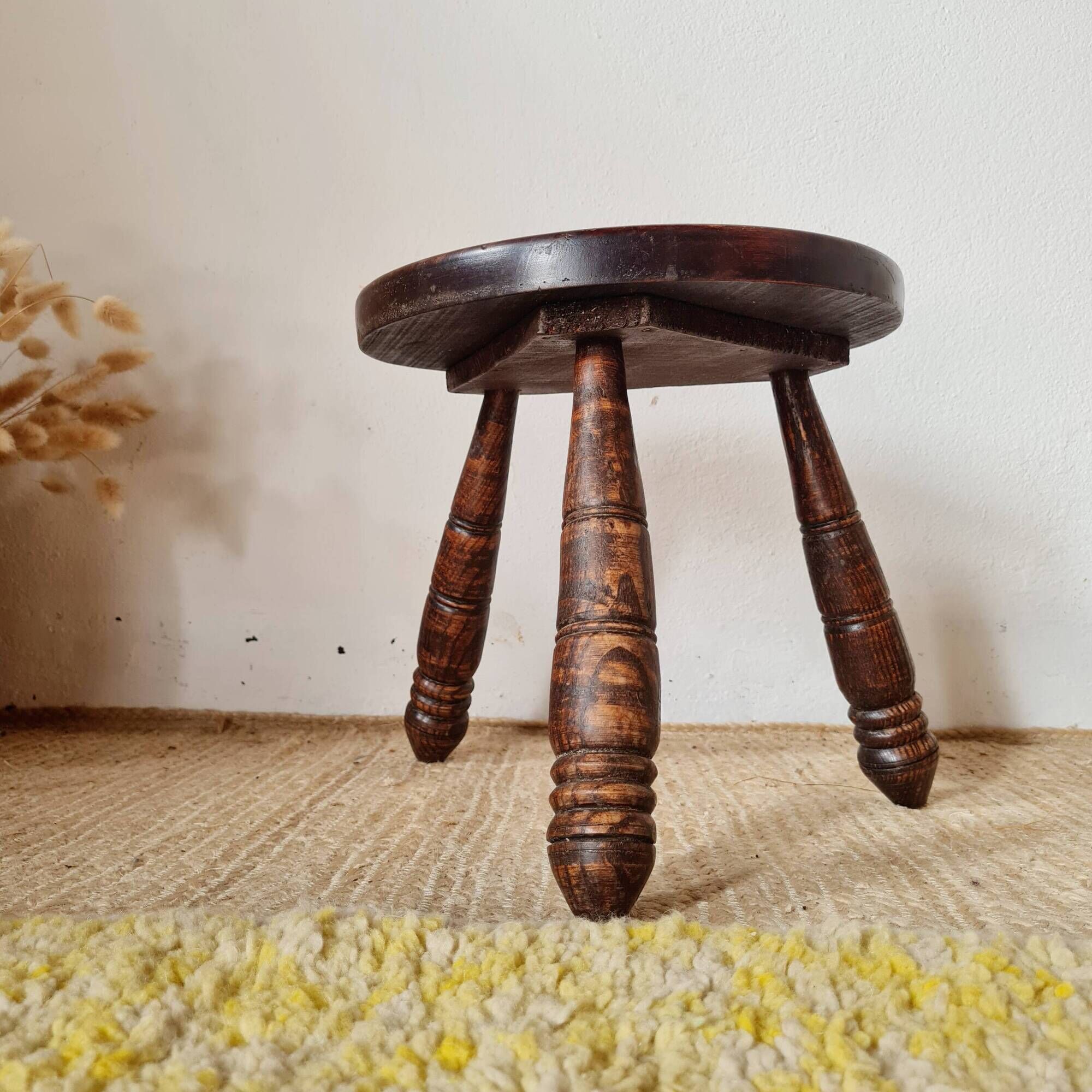 Small brutalist tripod stool made of turned wood.