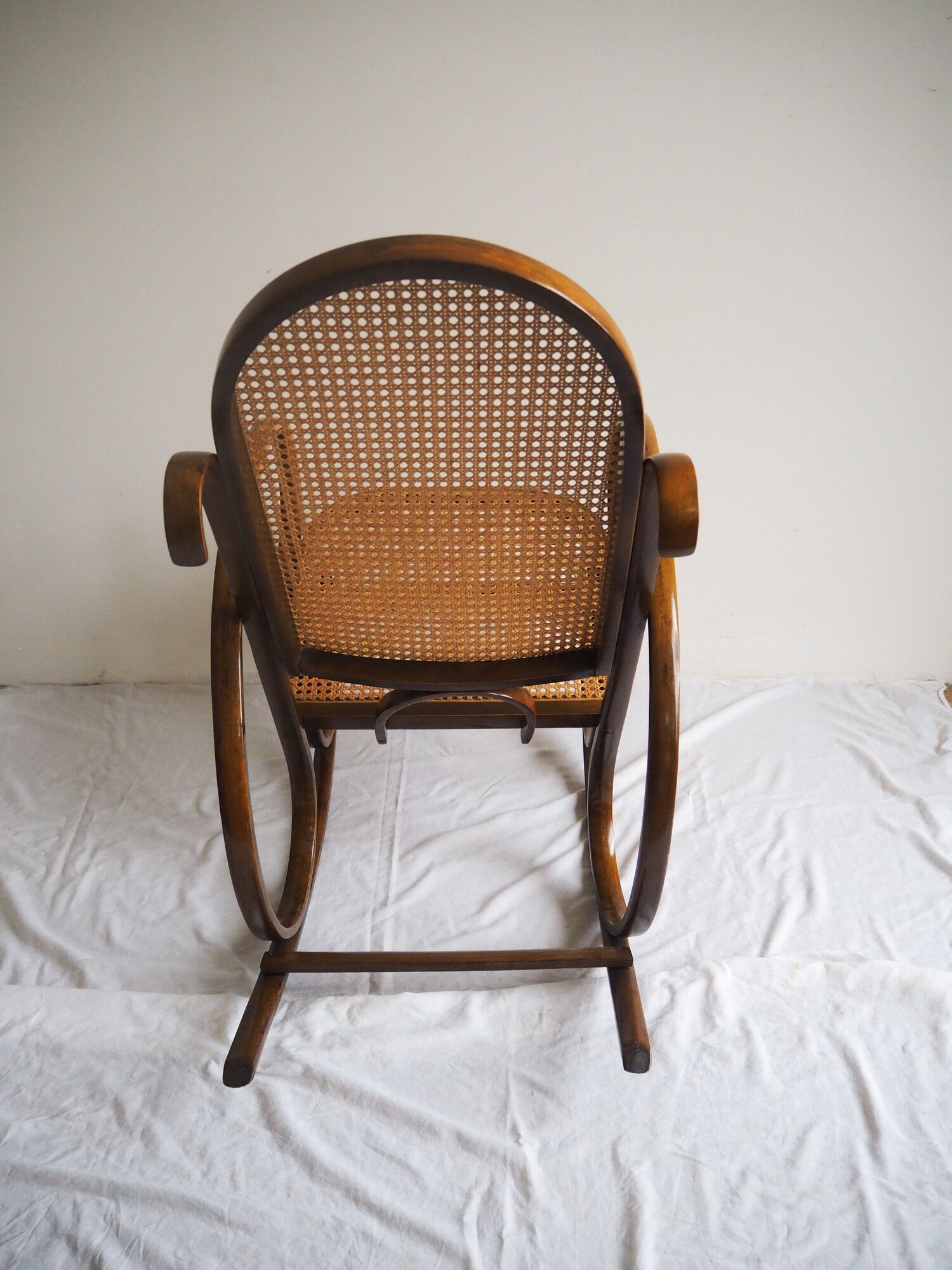 Rocking-chair en bois teinté et assise cannée