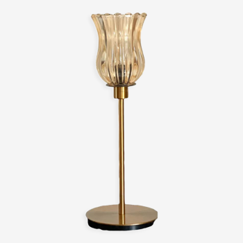 Table lamp with an old golden glass lampshade with pronounced edges and a golden foot