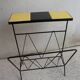 Black metal magazine rack and yellow and black tiled shelf.
