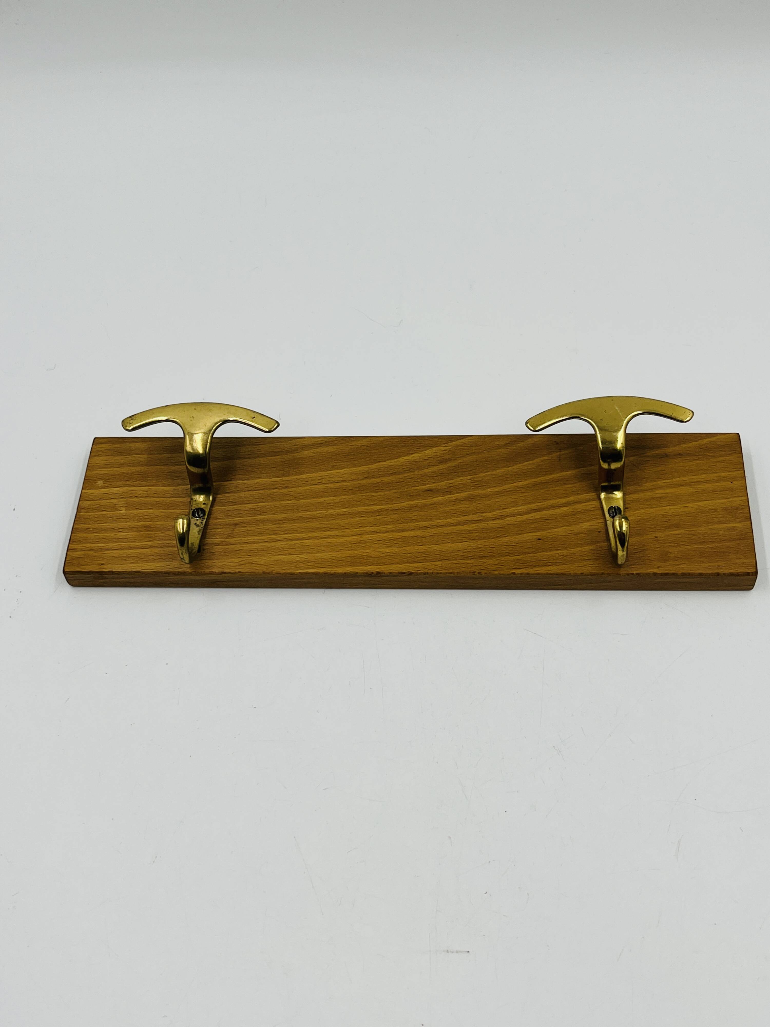Vintage wall coat rack in brass and wood design.