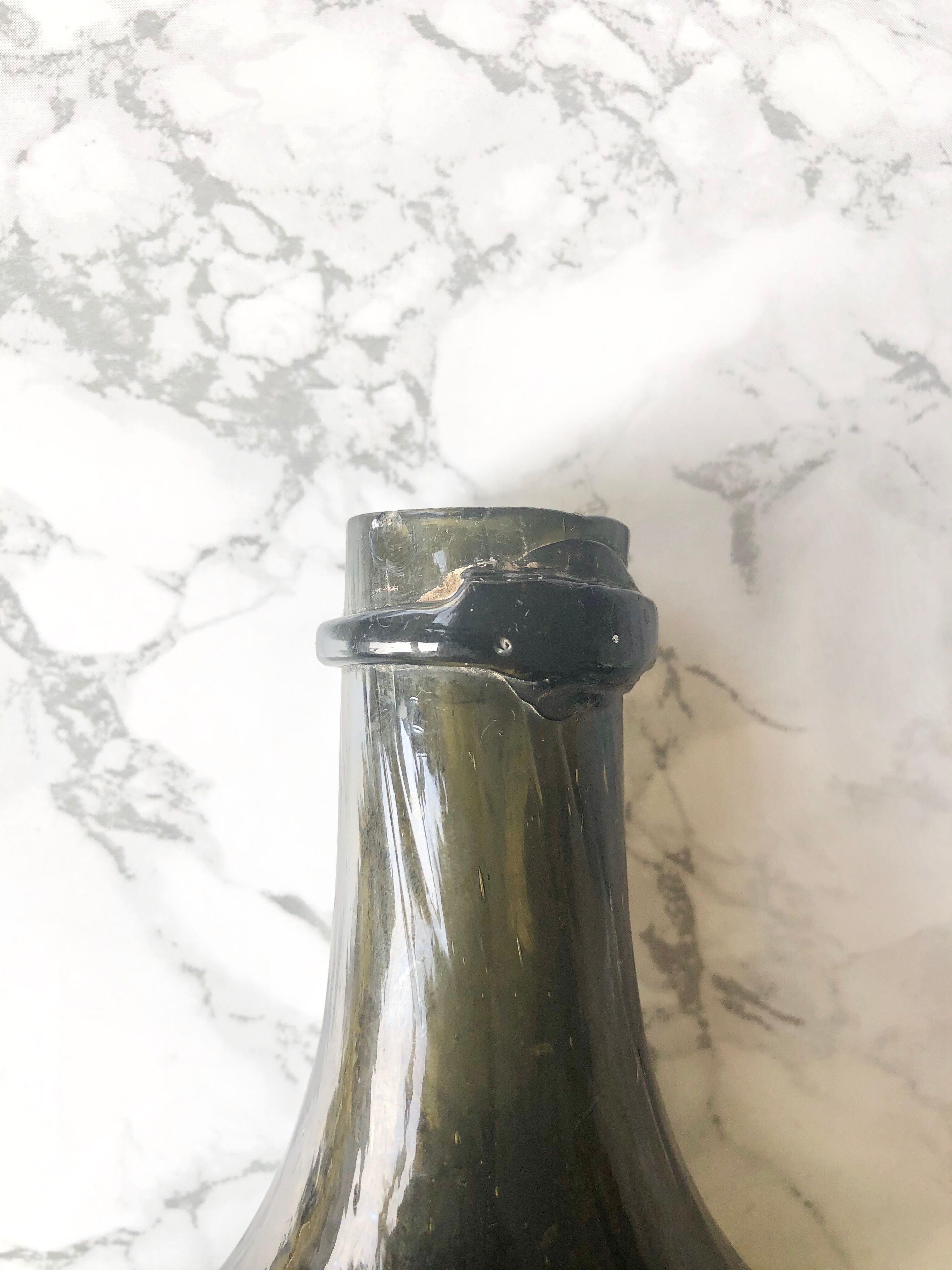 Old rum bottle in thick puffed glass in dark green color