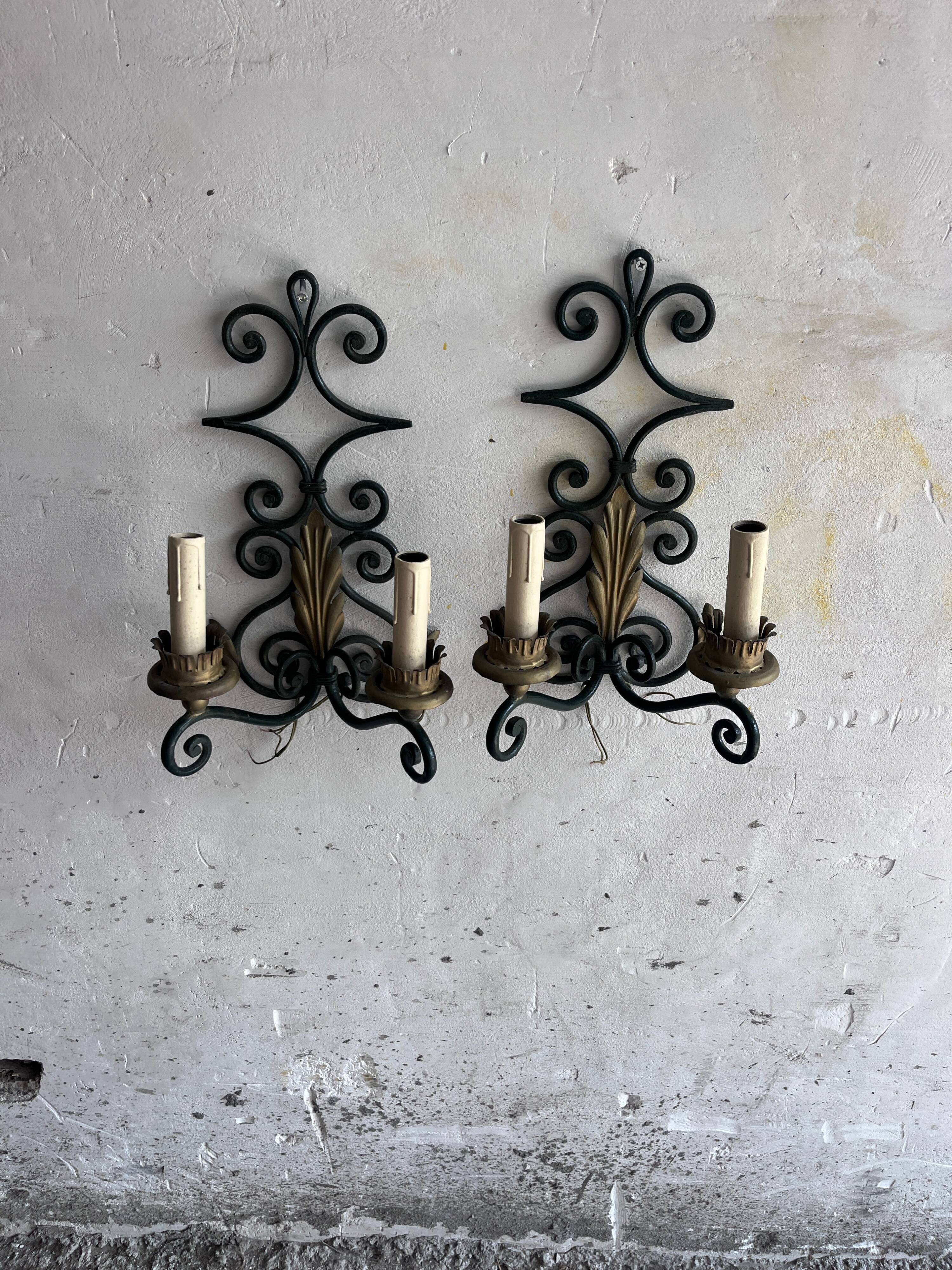 Pair of wall sconces in wrought iron with golden leaf patterns.