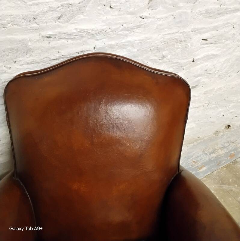Antique club chair with gendarme hat back