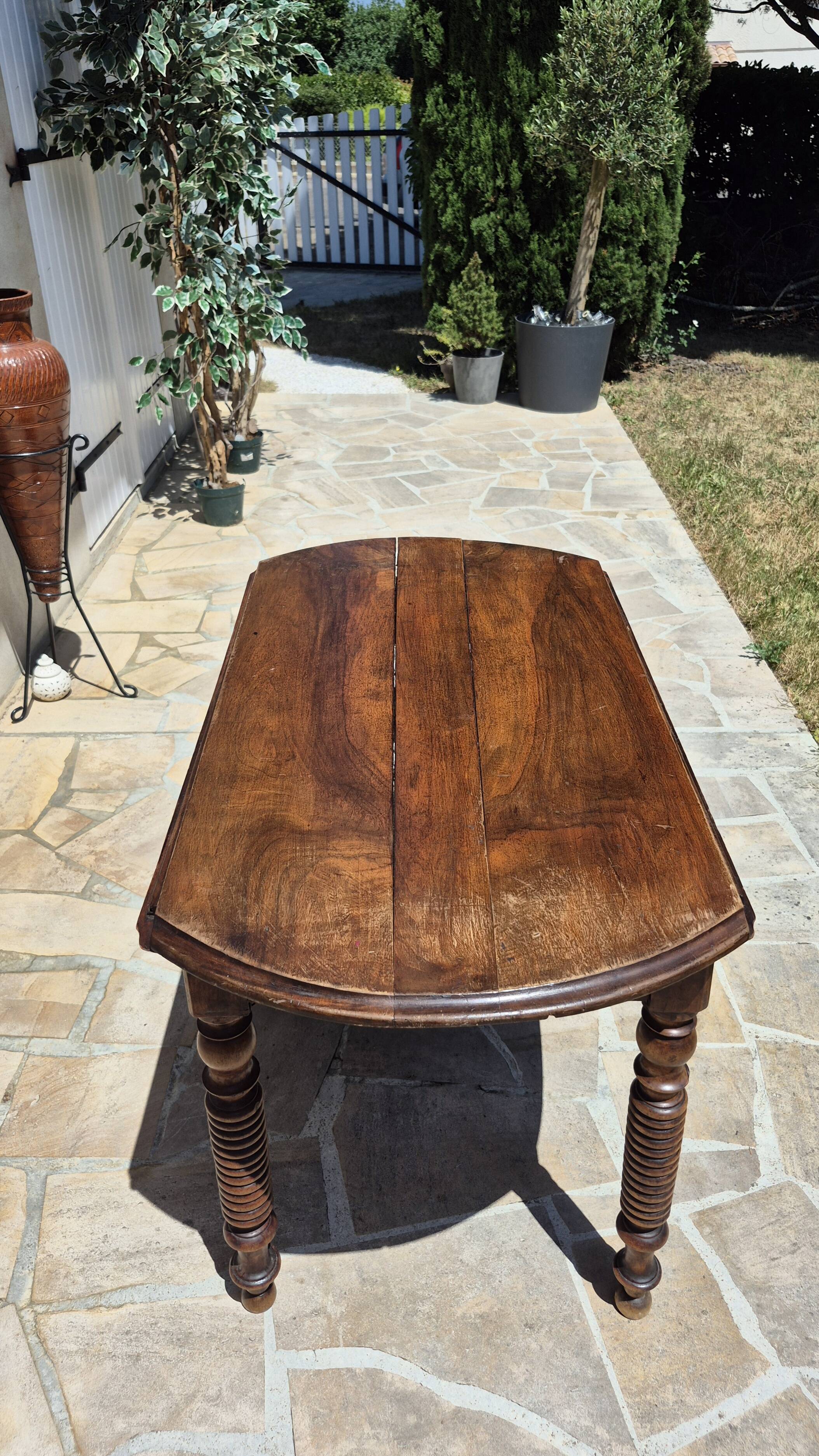 Round dining table with a drop-leaf top in solid walnut, late 19th century.