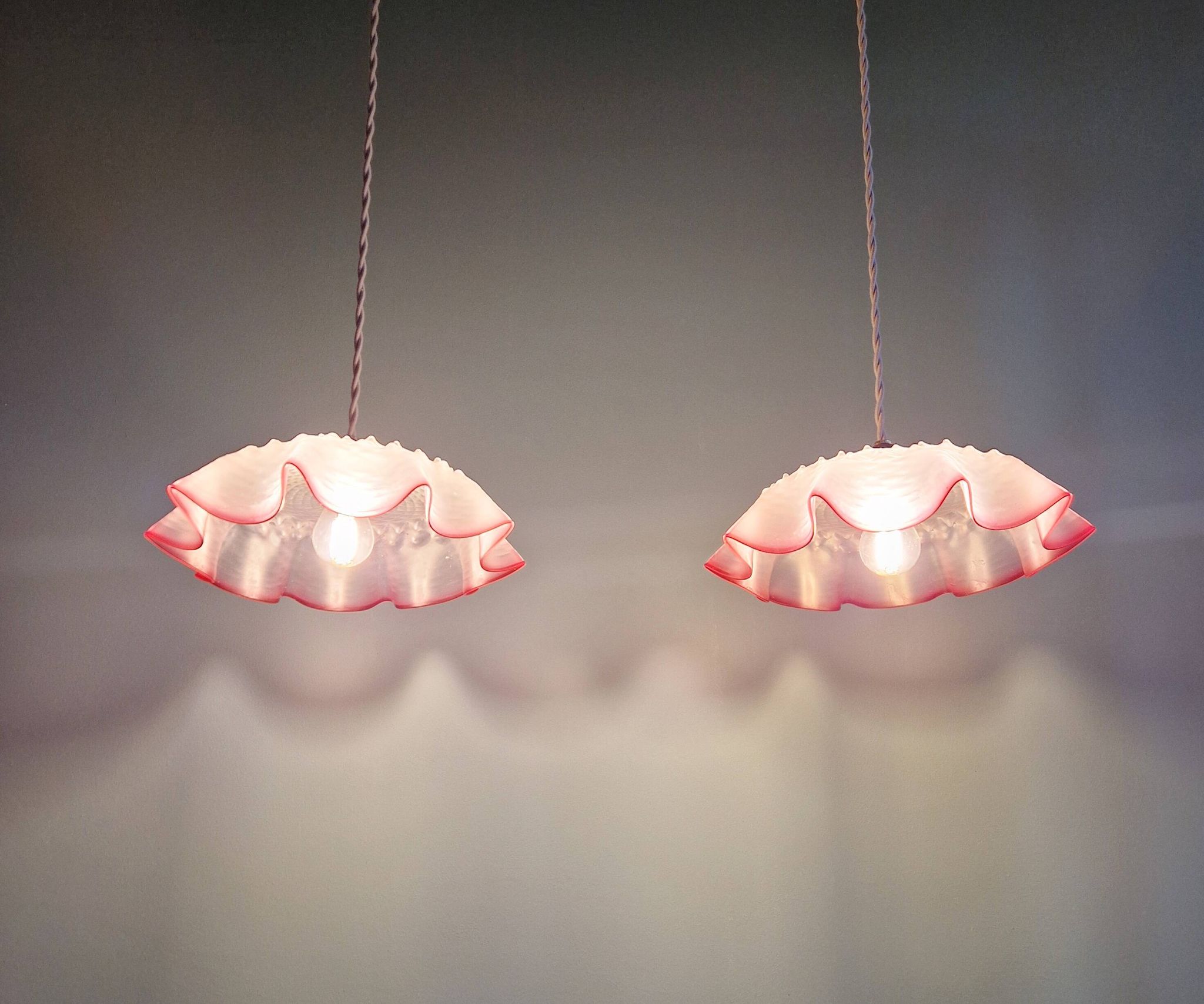Pair of clear and pink satin glass scalloped pendant lights, 1920s-30s