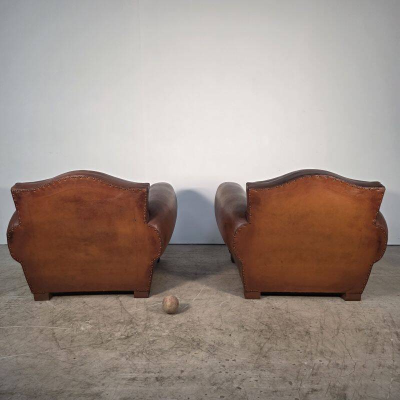 Important pair of Havana leather club armchairs, moustache models, mid-20th century.