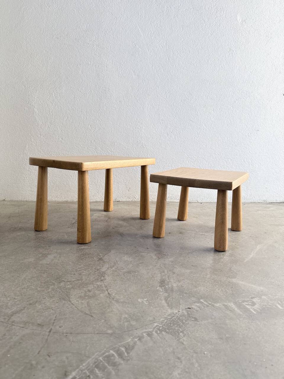 Two stools or small nesting tables in light oak.