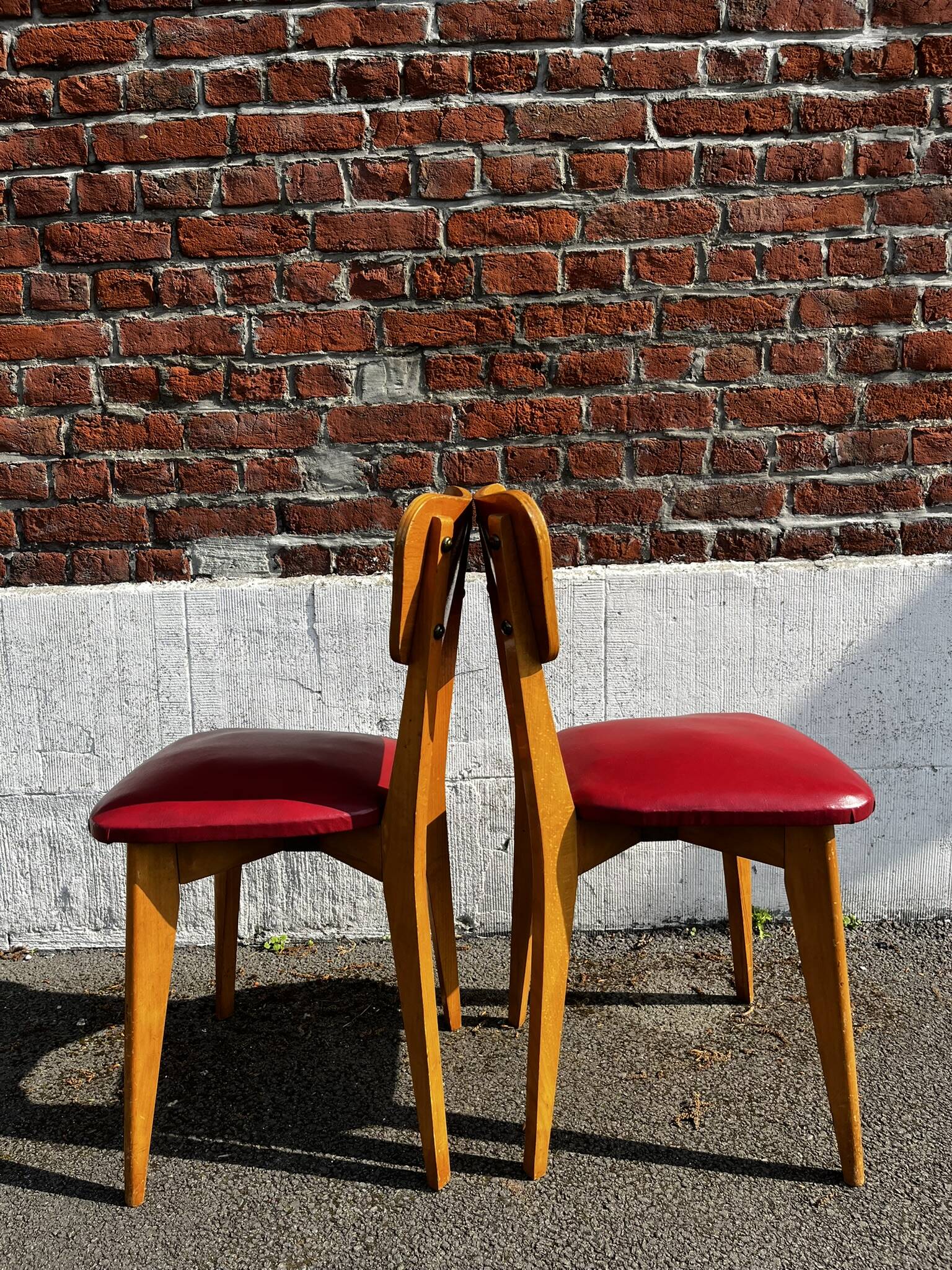 Set of 4 vintage bistro chairs in wood and red faux leather, with splayed legs.