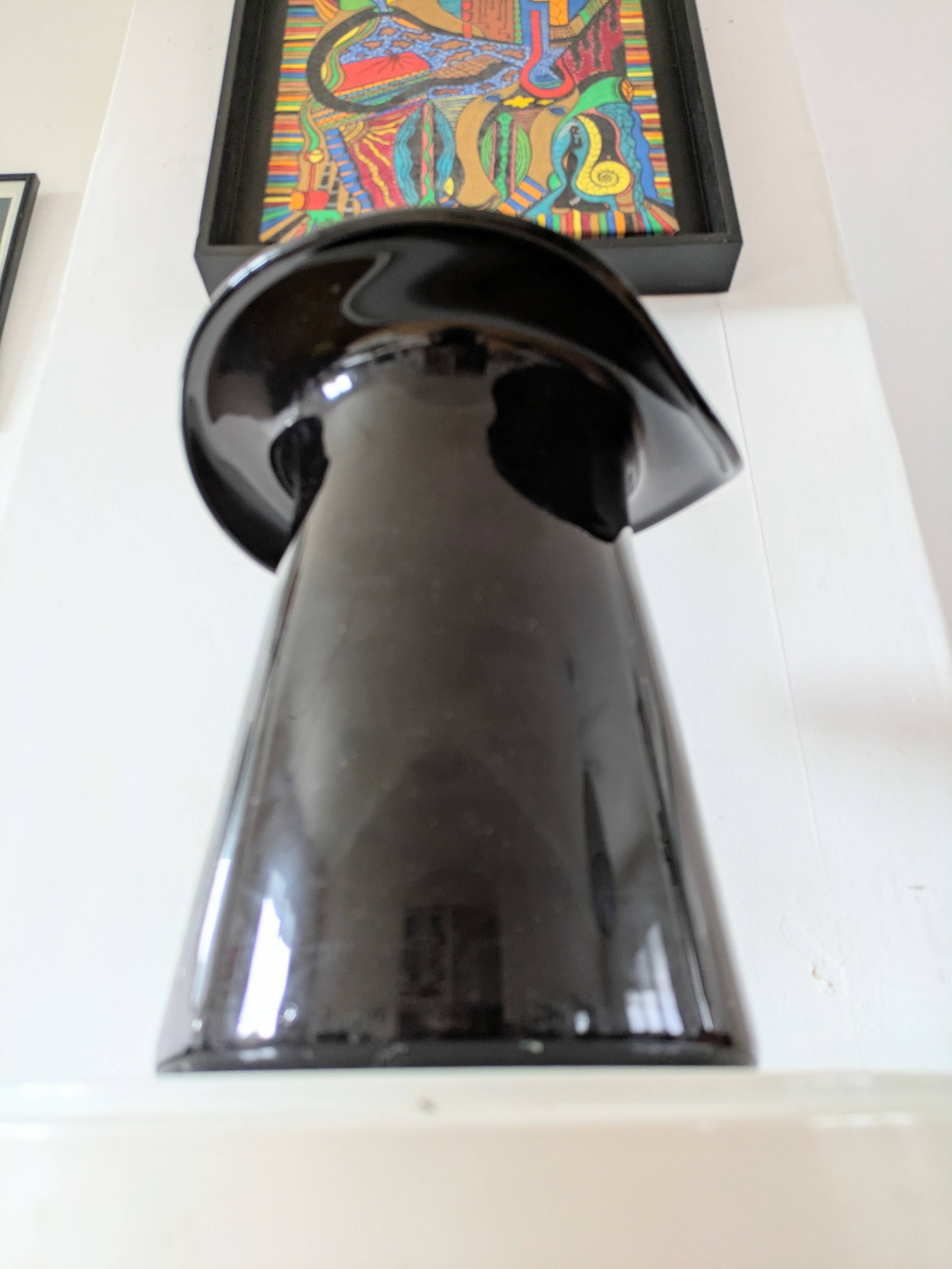 Large black glass vase topped with a 70s hat