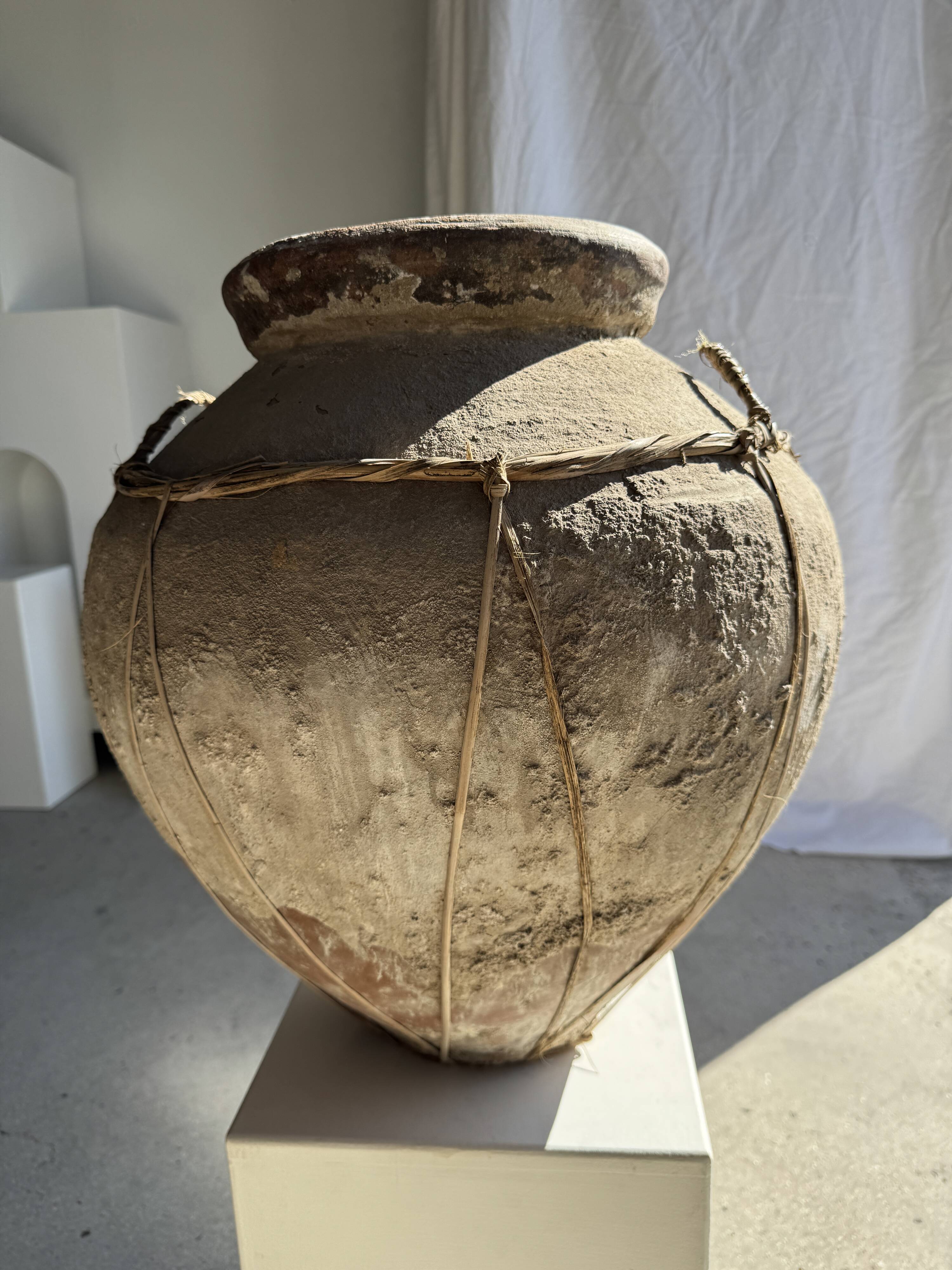 Very large grey and red terracotta pot with handles and rattan crossbars.