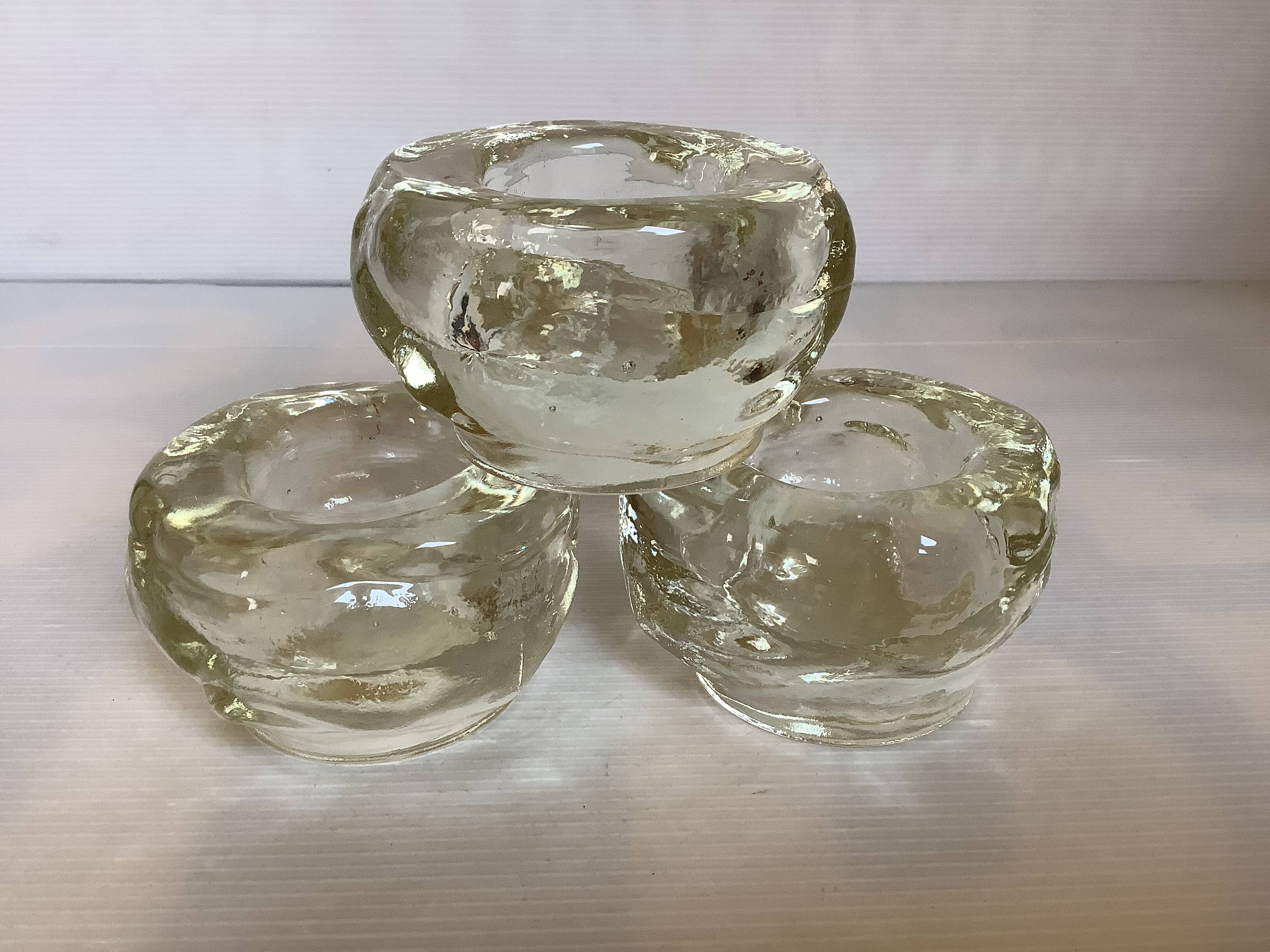 Set of three thick moulded glass candle holders.