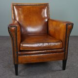 Art deco armchair in sheepskin with black piping and decorative nails