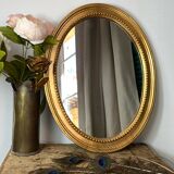 Oval-shaped wooden mirror in gold color