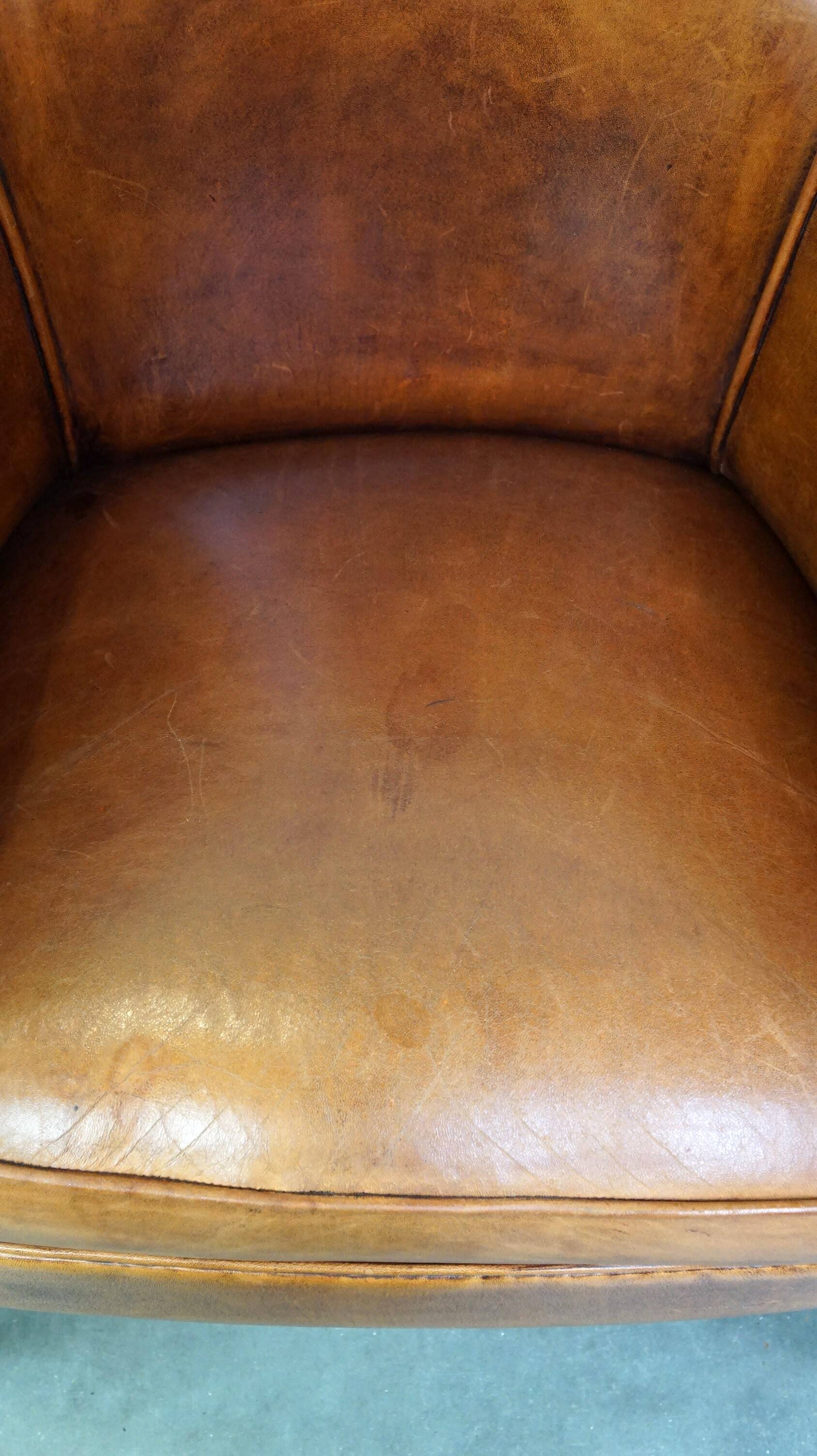 Neat and subtle sheepskin club chair, finished with decorative studs and a fixed seat cushion