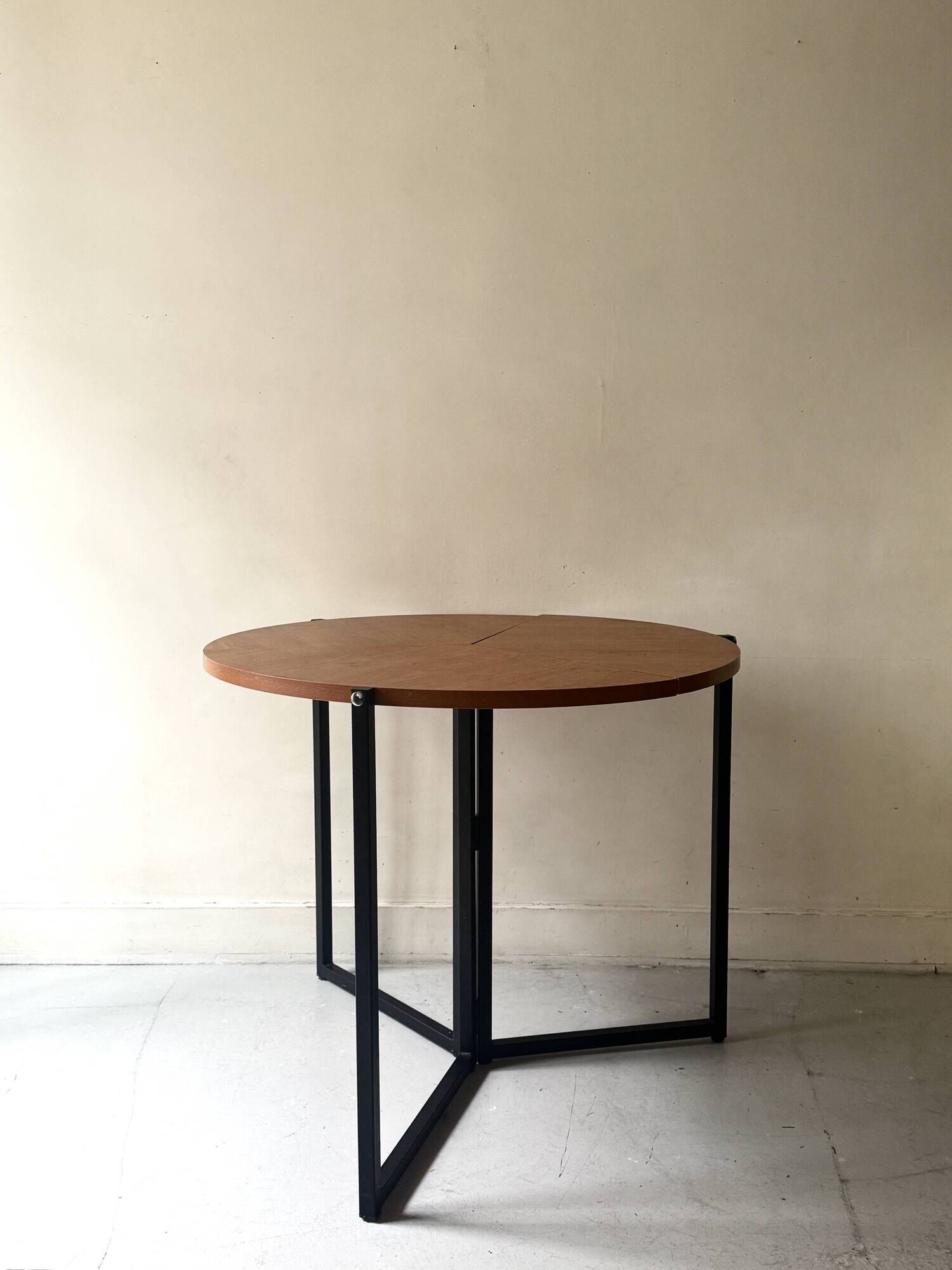 Modernist round folding dining table in wood and metal.