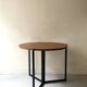 Modernist round folding dining table in wood and metal.