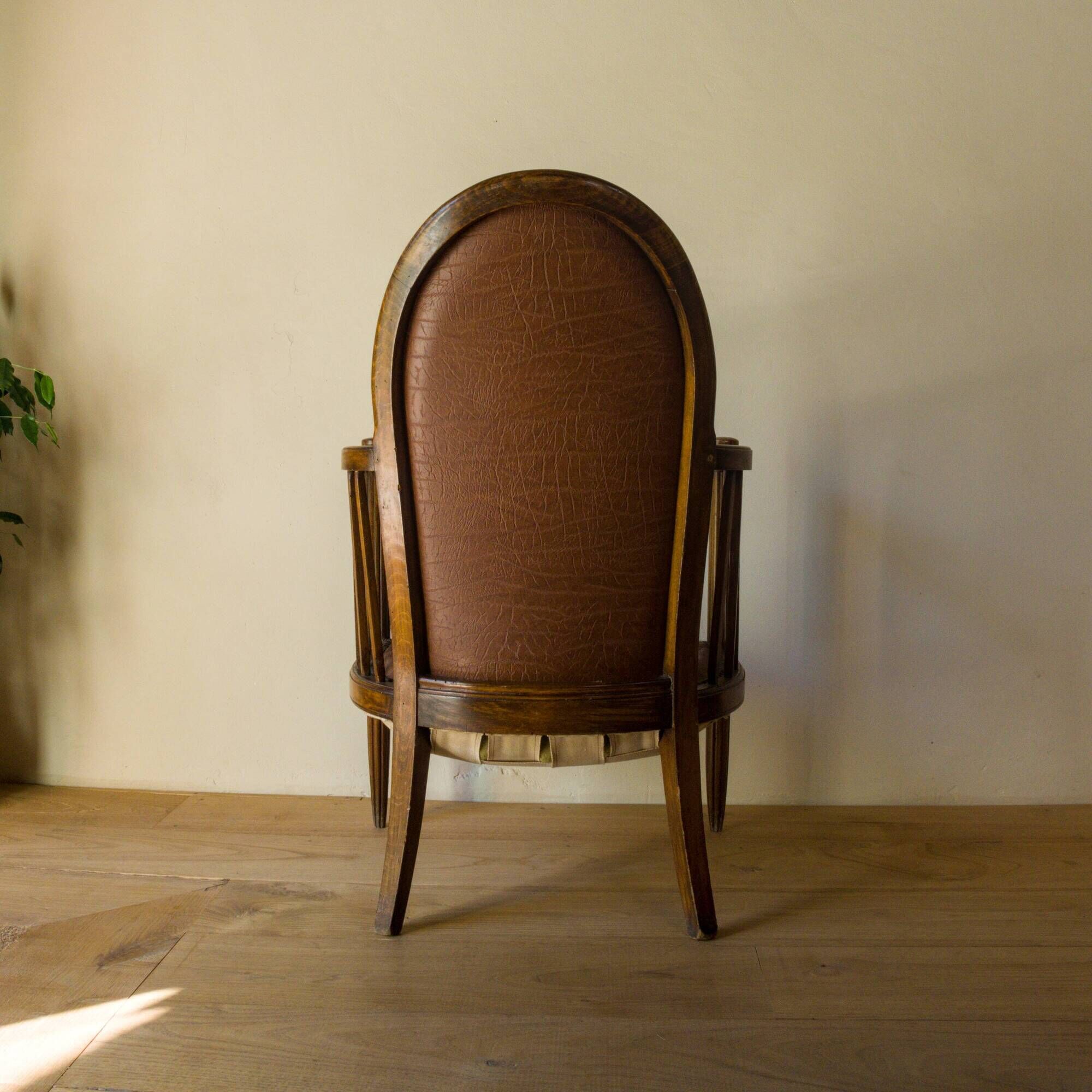 Antique armchair in solid wood and patinated brown leather, early 20th century.