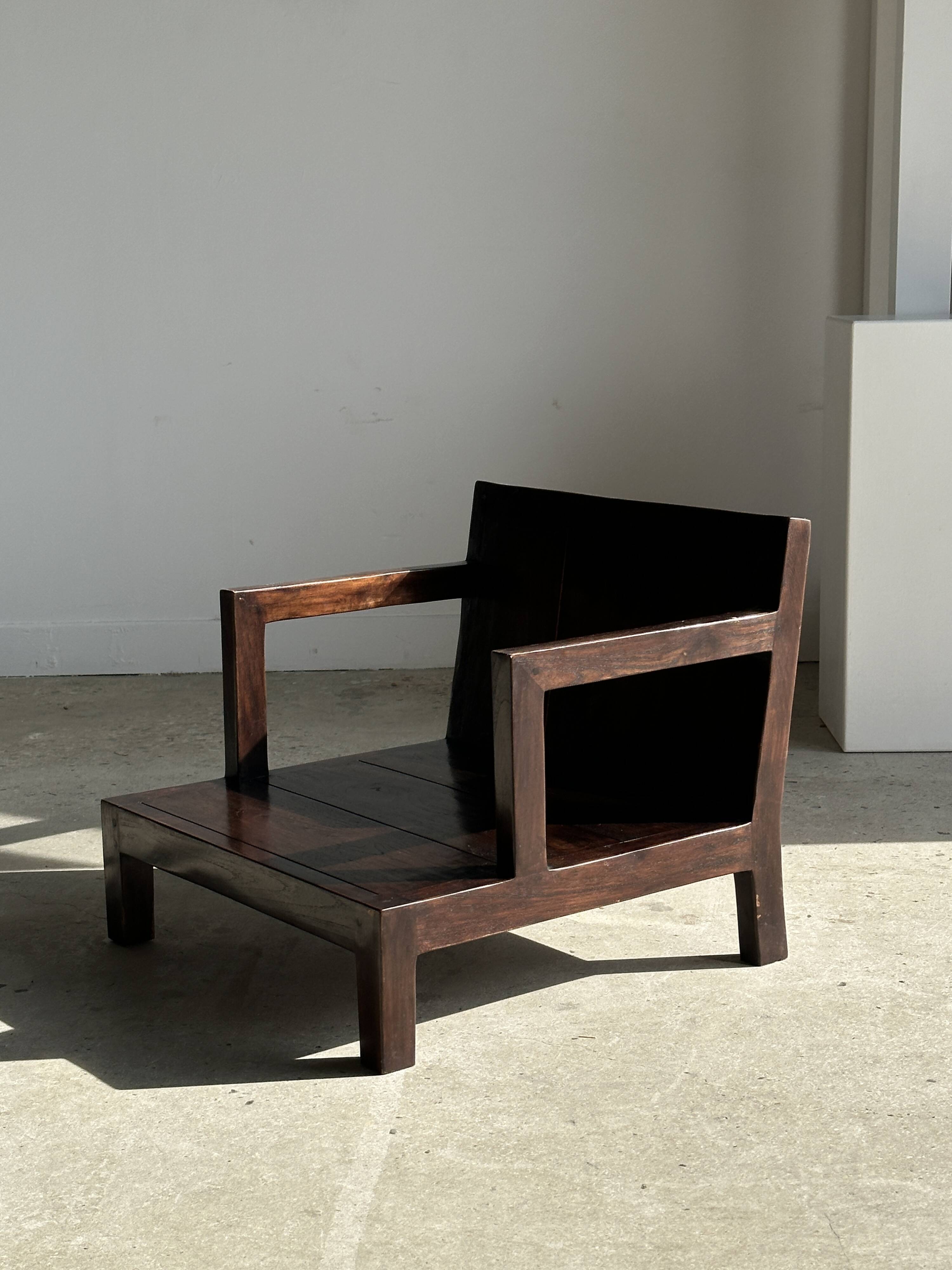 Small low armchair in varnished brown wood