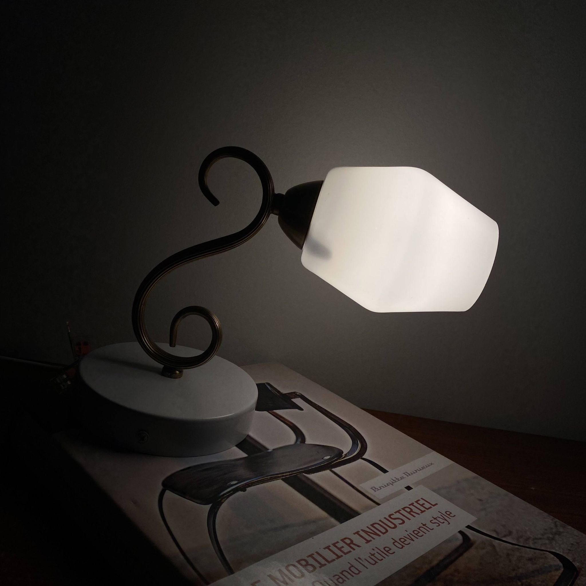 Swan neck wall light in brass with a white glass shade.