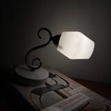 Swan neck wall light in brass with a white glass shade.