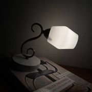 Swan neck wall light in brass with a white glass shade.