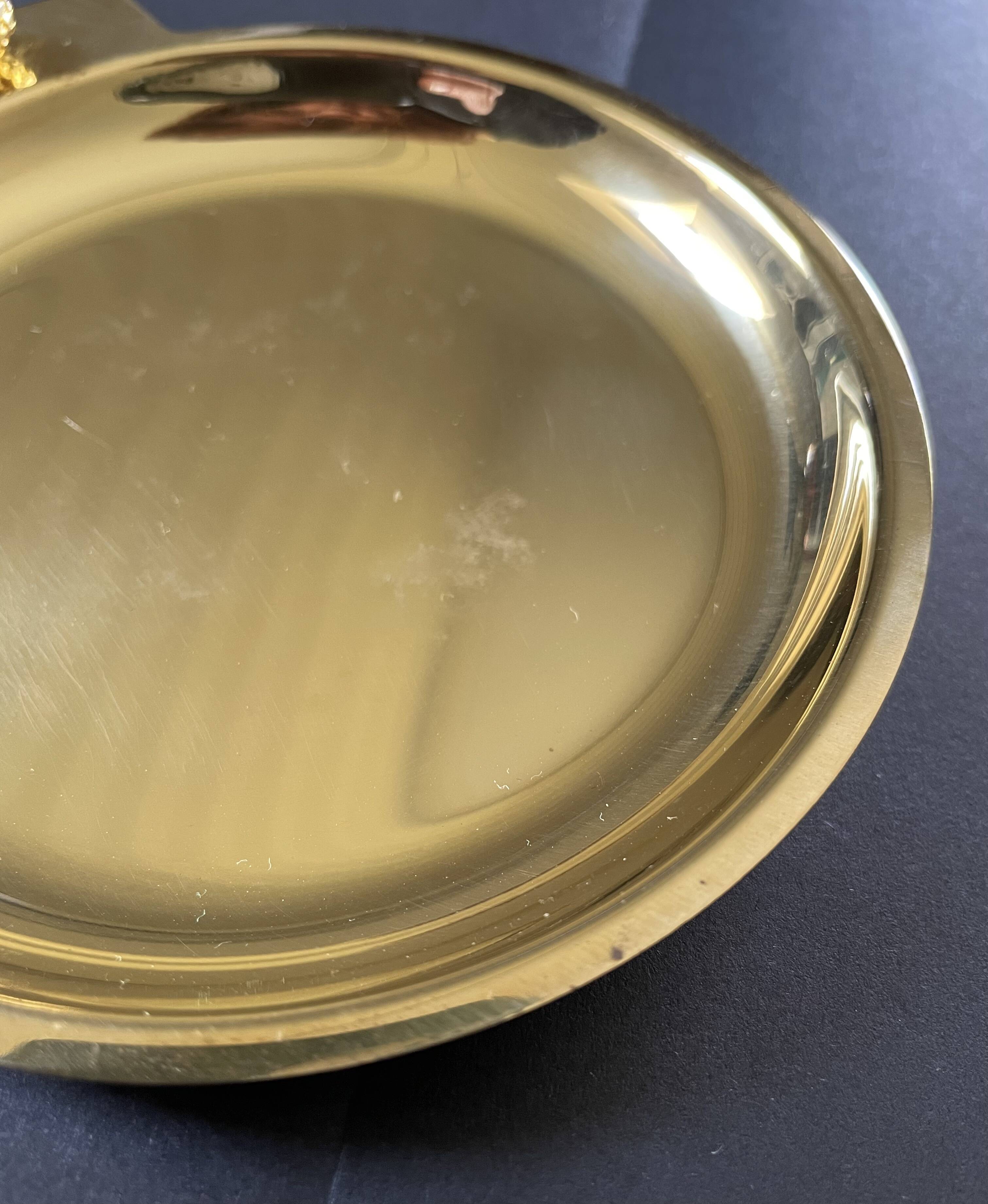 Round brass pocket tray with club and golf ball decoration.